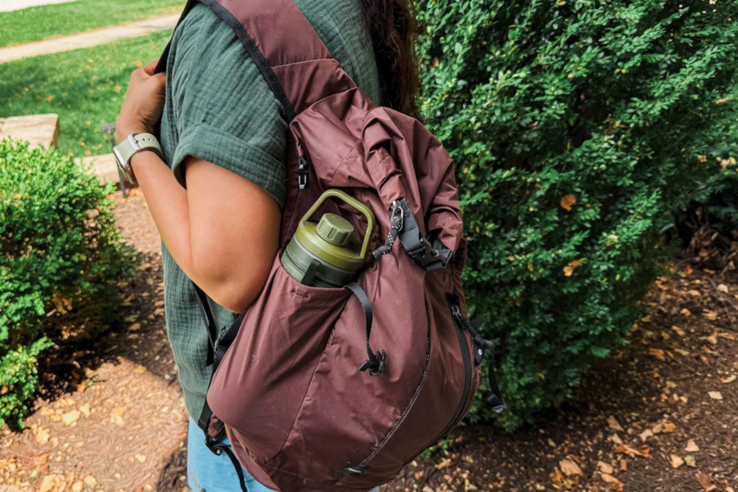 The author wearing the Matador 18L Waterproof Packable Backpack with a water bottle in a side pocket.