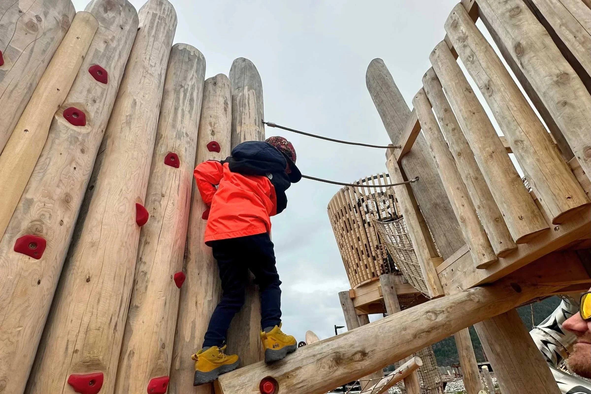 Child testing the North Face Antora rain jacket at a wooden playground structure