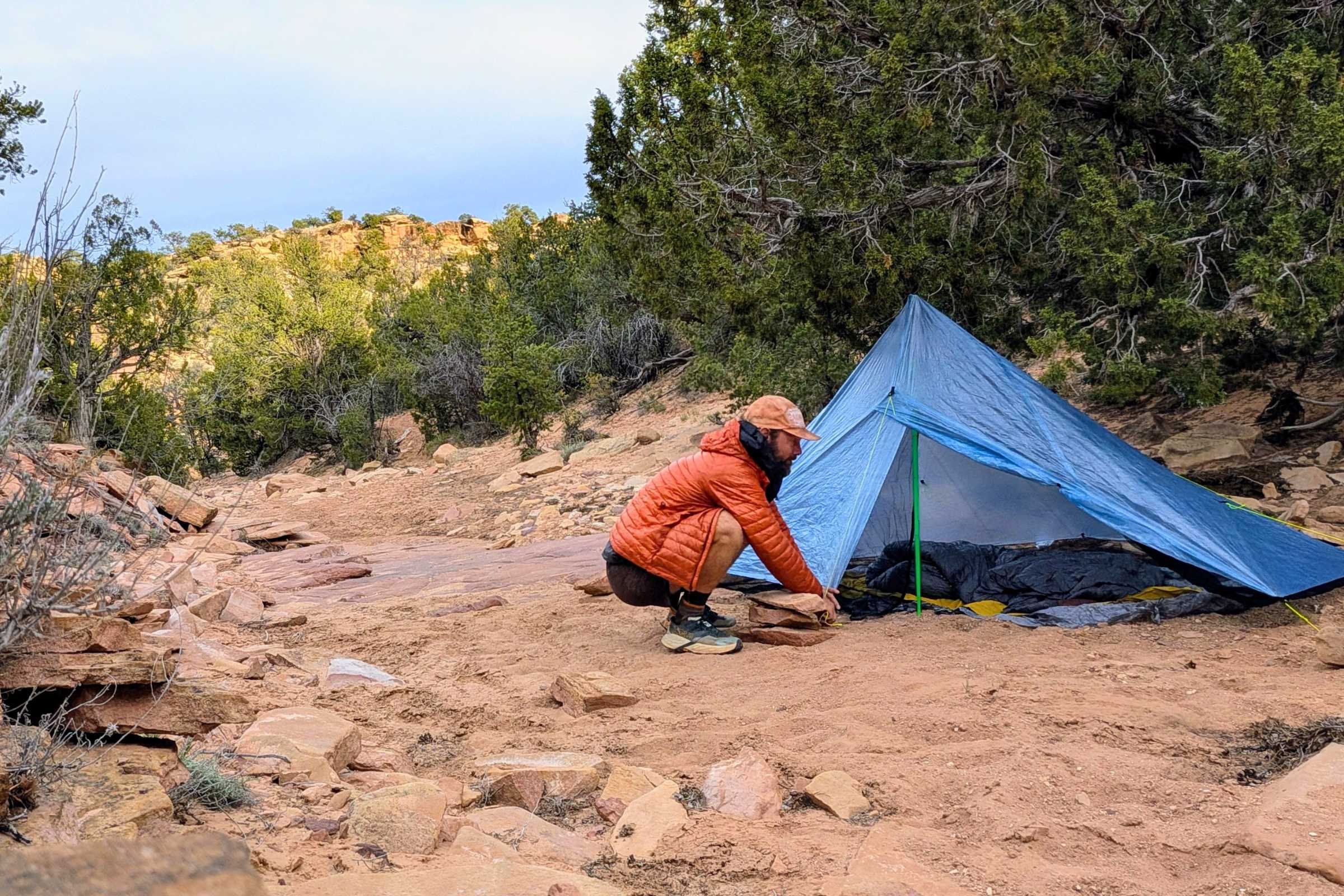 Man setting up a Zpacks Hexamid Ultralight Tent on a rocky trail.