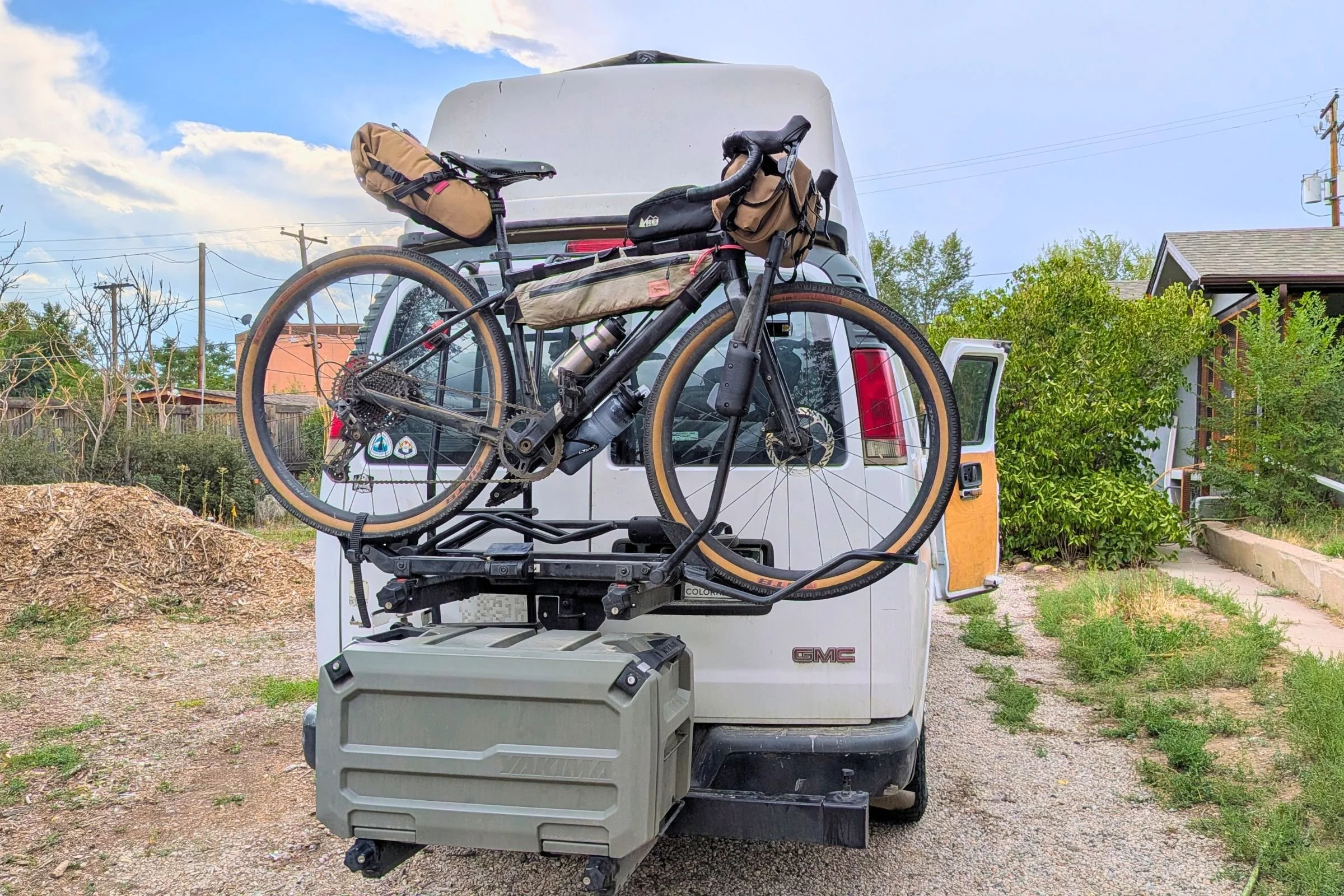 A bike is mounted on a Yakima EXO DoubleUp 2-Bike Hitch Rack attached to the back of a van.