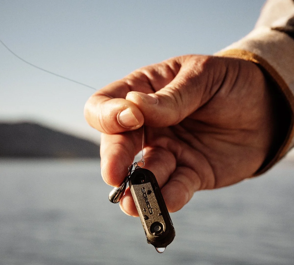 A closeup of a hand holding the COROS HYDROP with water dripping off it