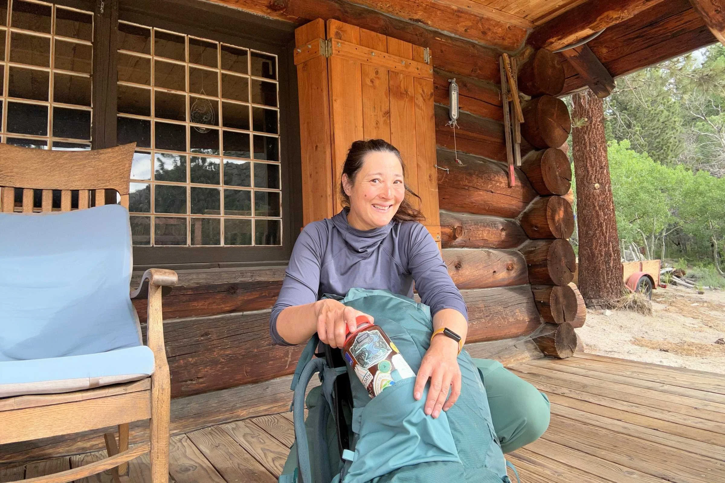 Woman sitting on a porch with the Osprey Fairview Trek 55 Travel Pack beside her.