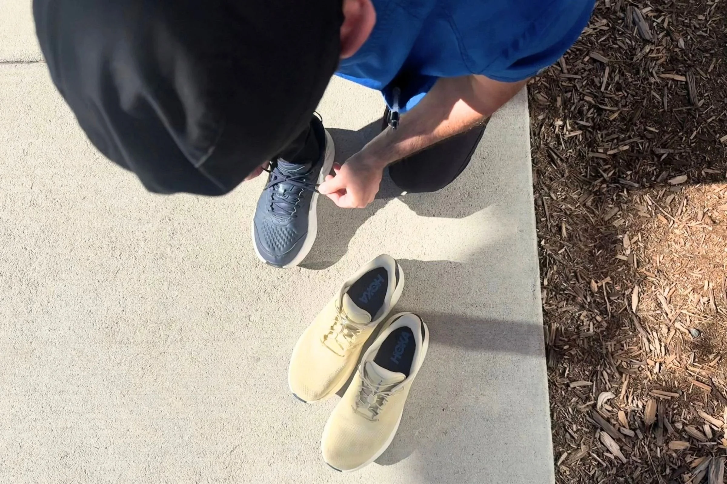 Man tying HOKA Bondi SR with HOKA Arahi SR next to him