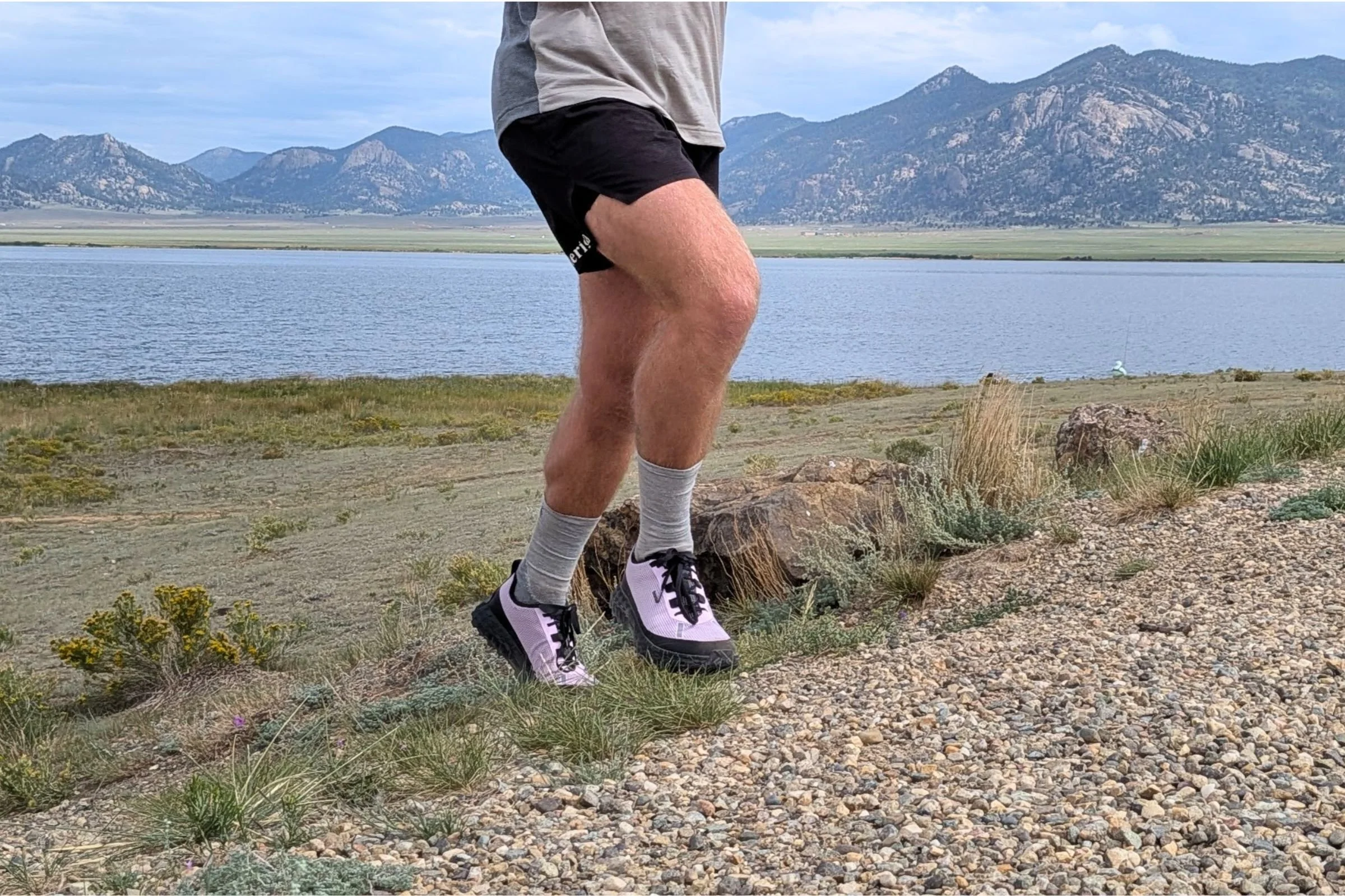 Man in shorts and a shirt running on a trail while wearing Norda 000 Trail Running Shoes.