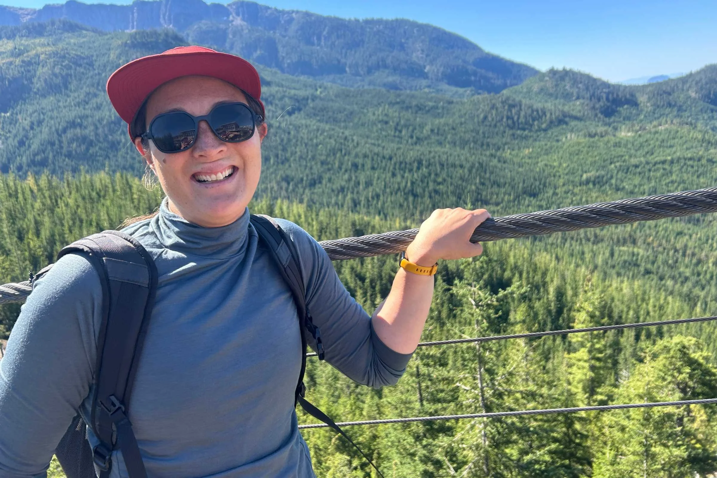 Liz Thomas wearing the ULA Ultra Dragonfly 30L Adventure Travel Backpack with mountains and trees in the background