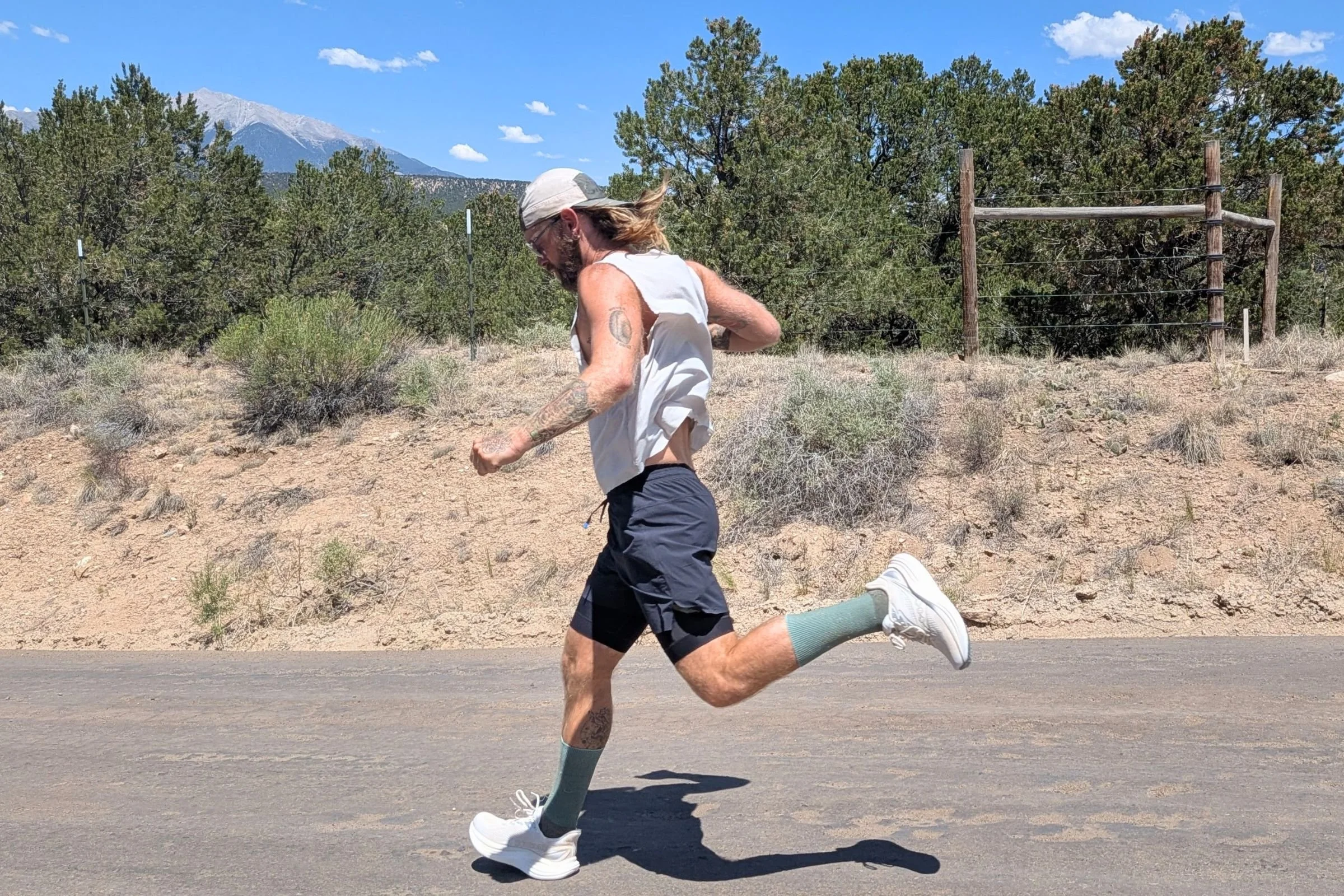 A man wearing shorts and a hat running on a road in the Saucony Triumph 24 Road Running Shoe.