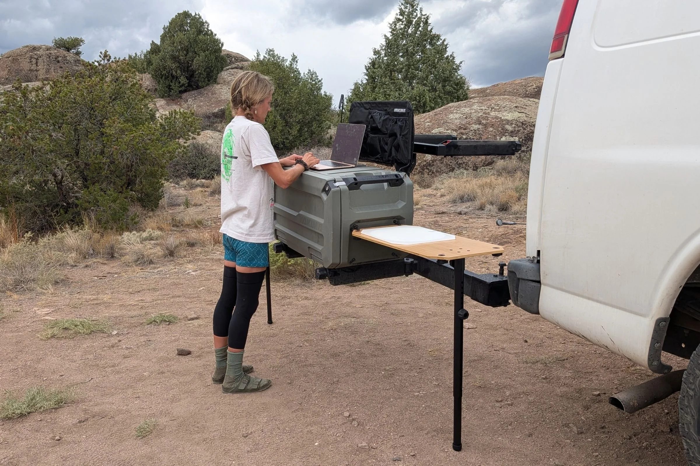 Person standing beside a vehicle and using the Yakima EXO OpenRange as a standing desk.