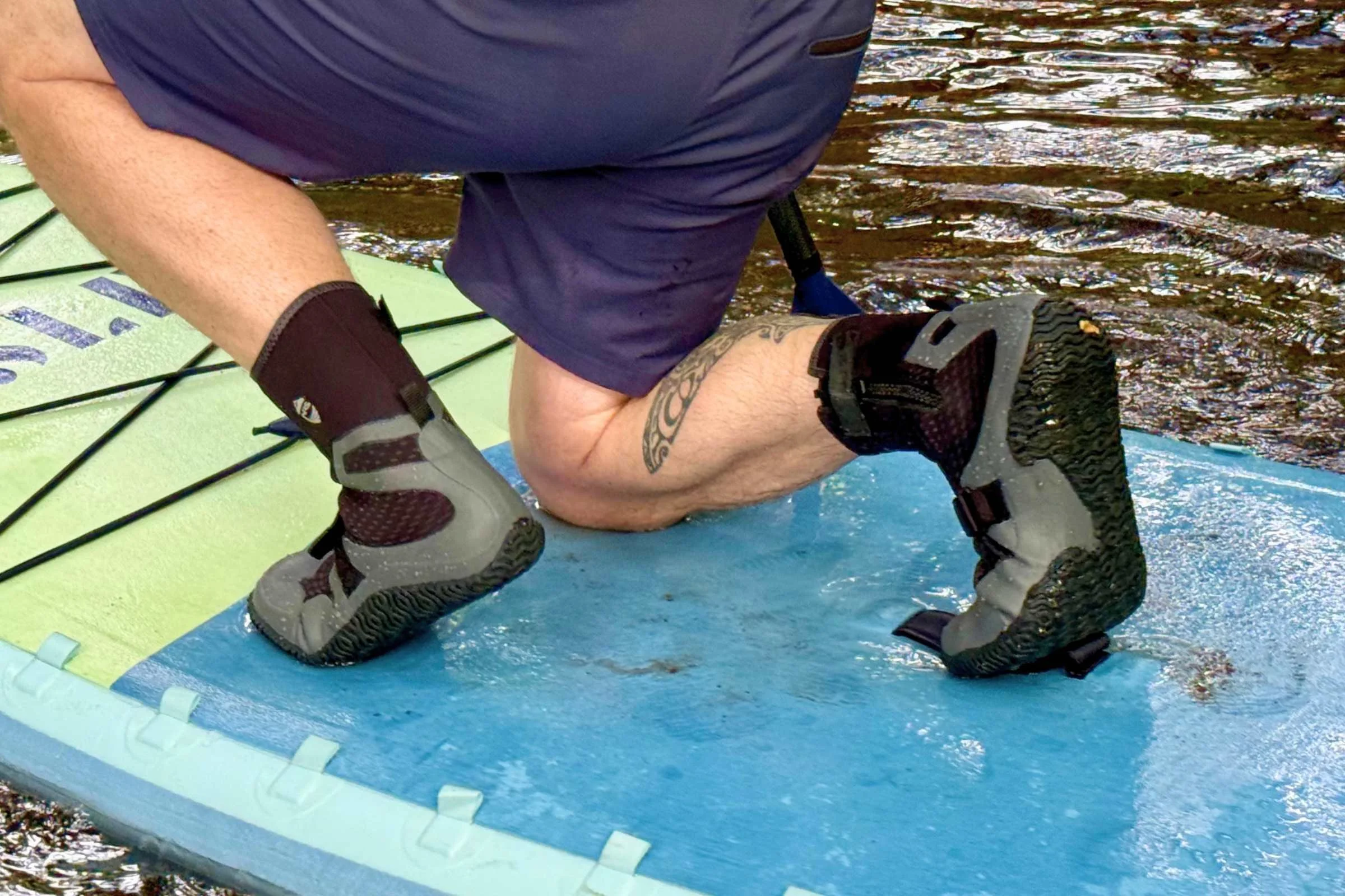 Person kneeling in the NRS Paddle Wetshoe on a SUP