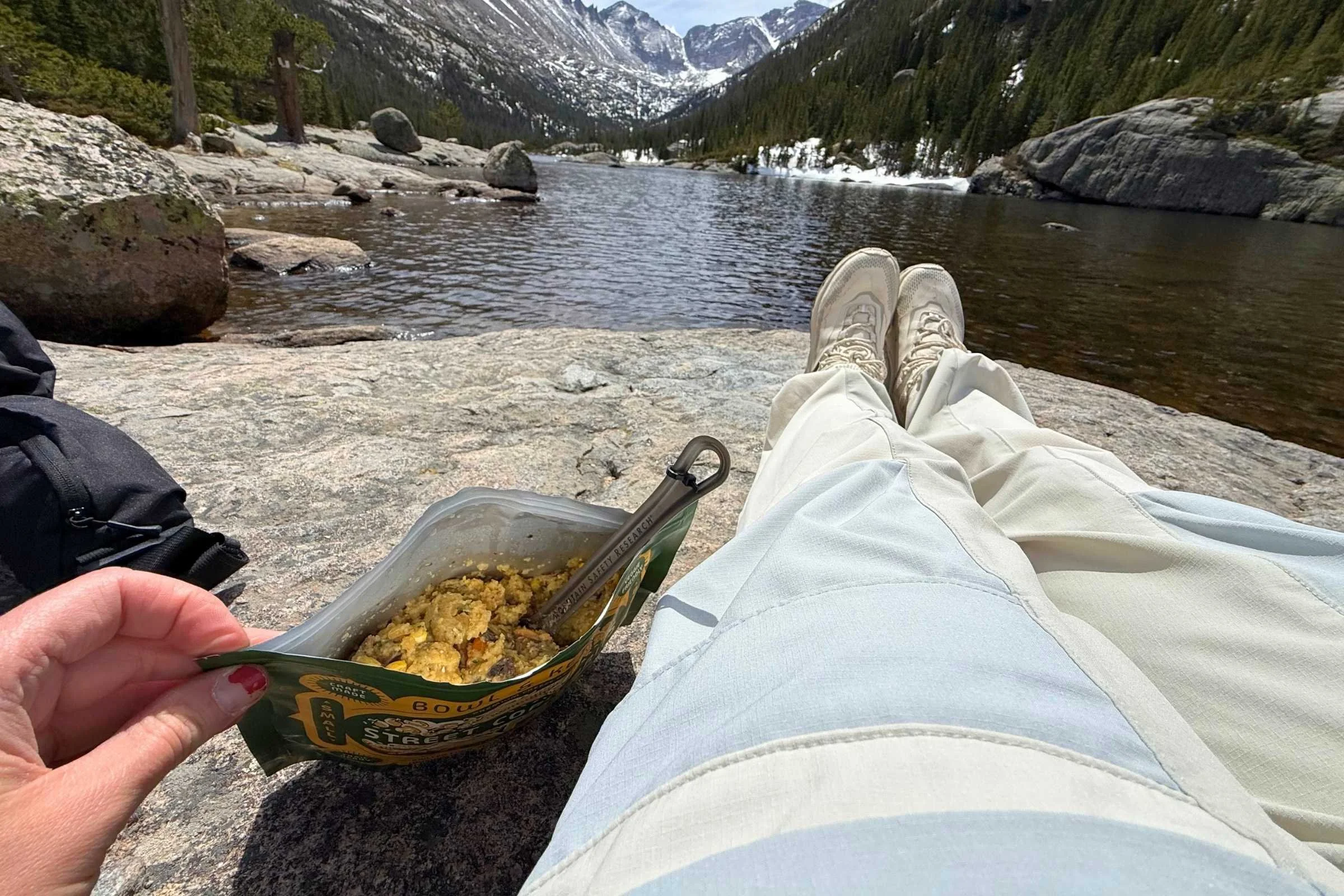 Prepared Bowl & Kettle Mexican Street Corn Grits freeze-dried meal being eaten beside a mountain lake.