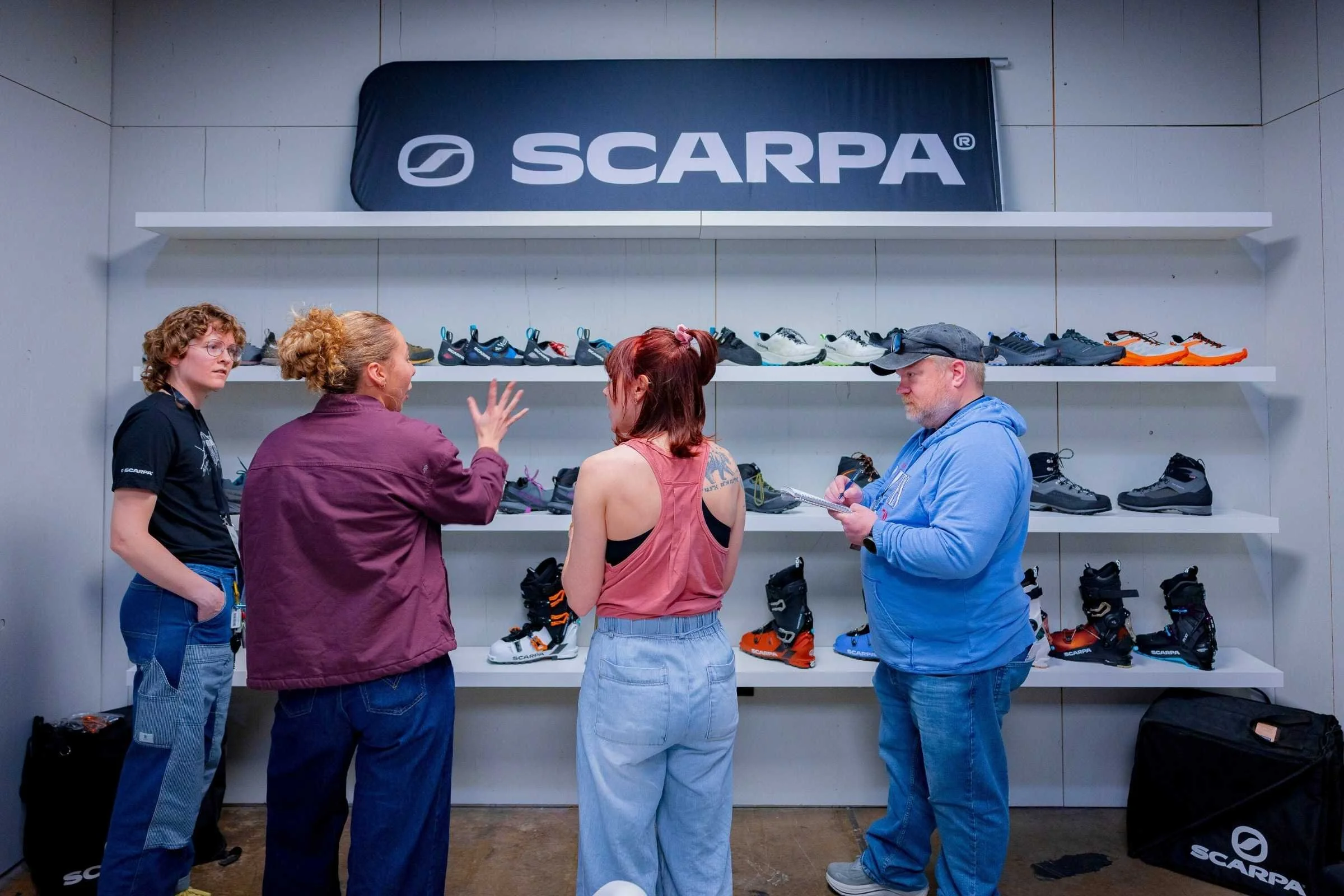 Treeline reviewer Becca learning about new trail running and crossover shoes at the SCARPA booth during the Outdoor Market Alliance show.