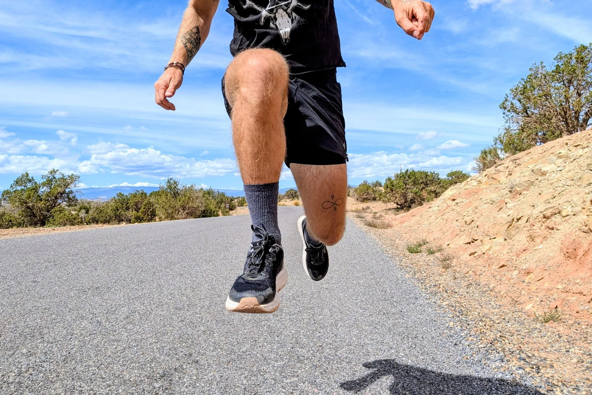 A man in mid-stride while running on a paved road while wearing the Lems ZENSPEED+ shoes.