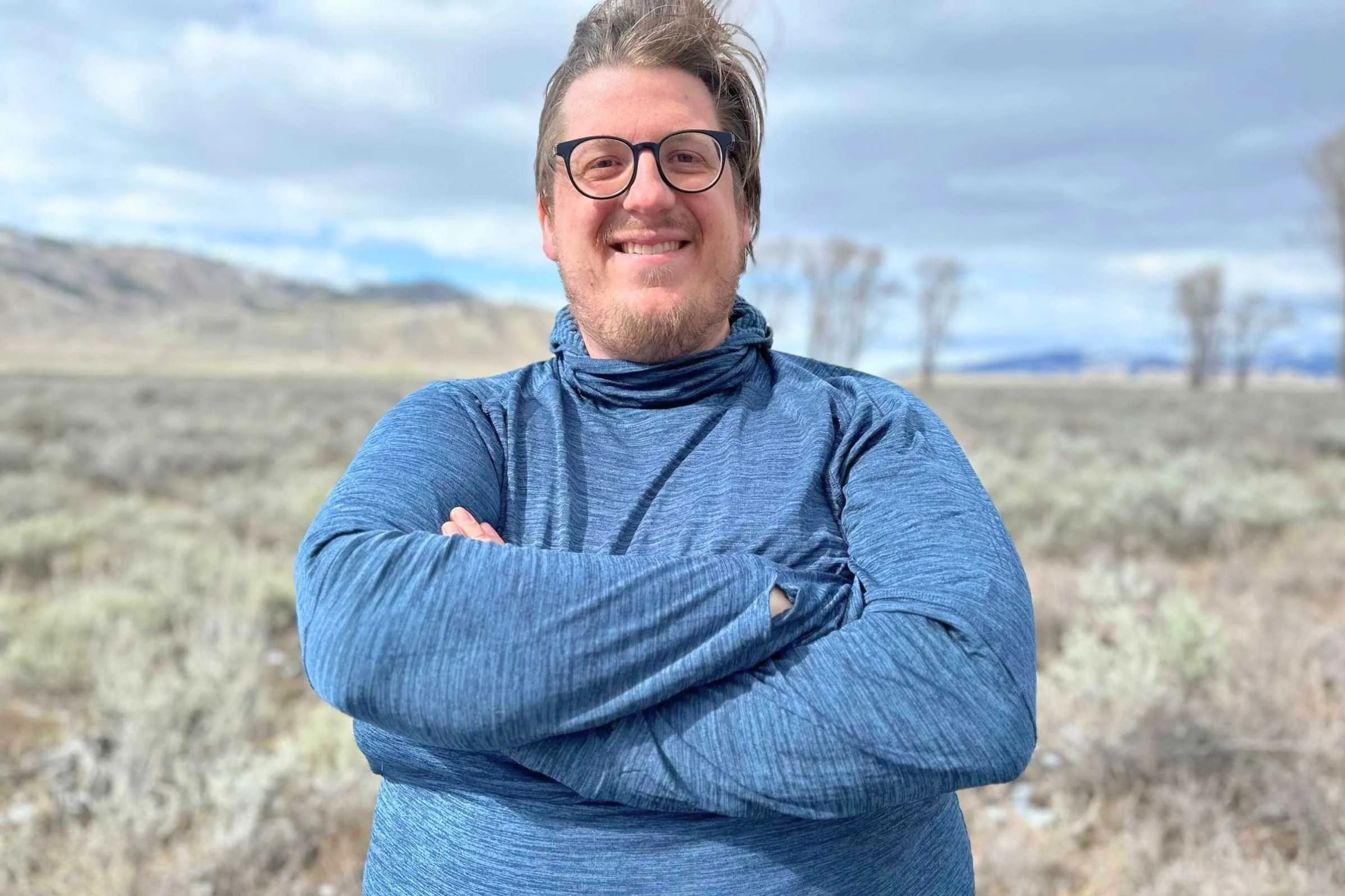 The author, Clayne Zollinger, standing in a field with mountains in the background.