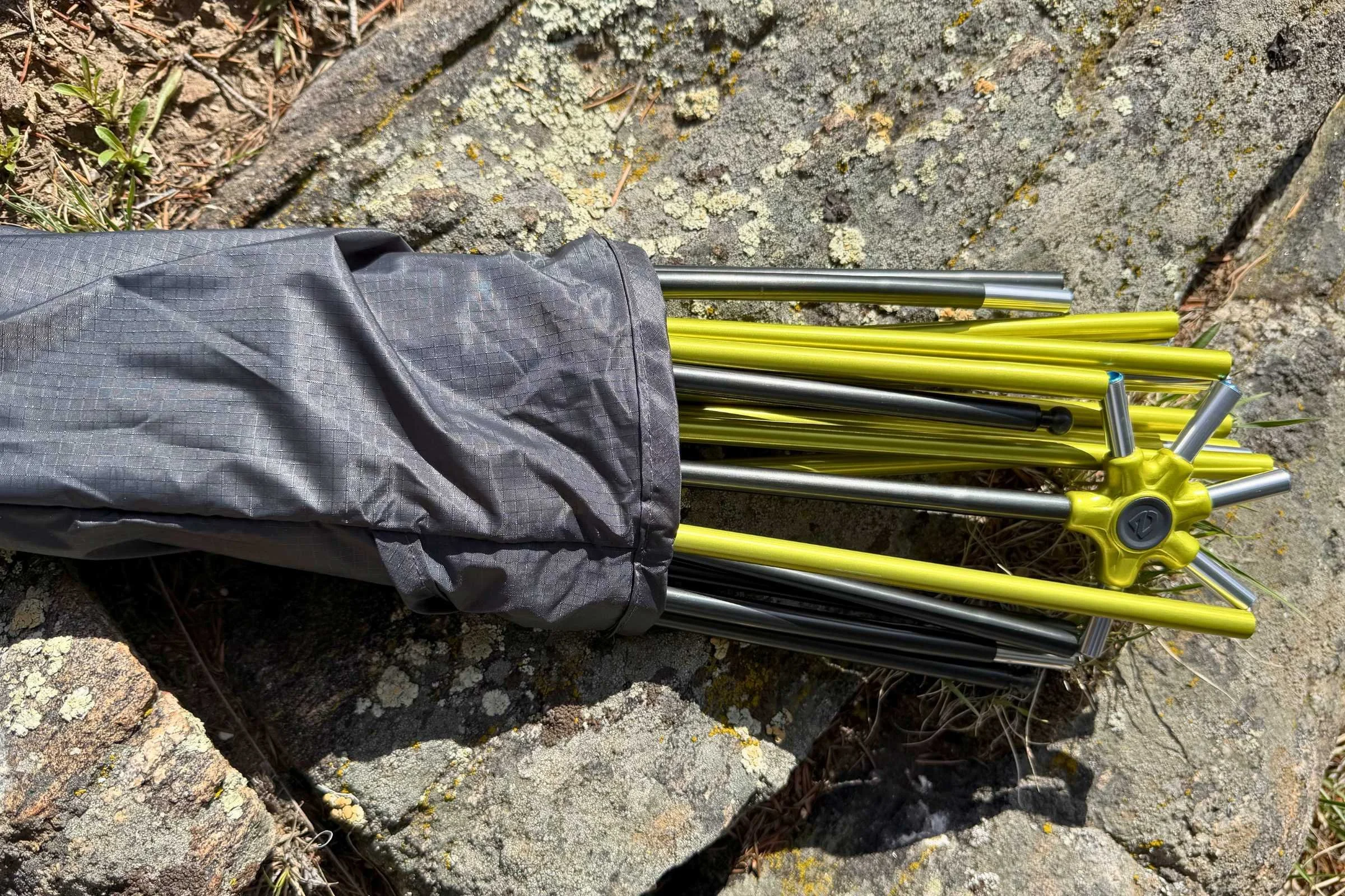 A closeup of the poles, folded up, partially inside the black pole stuff sack.