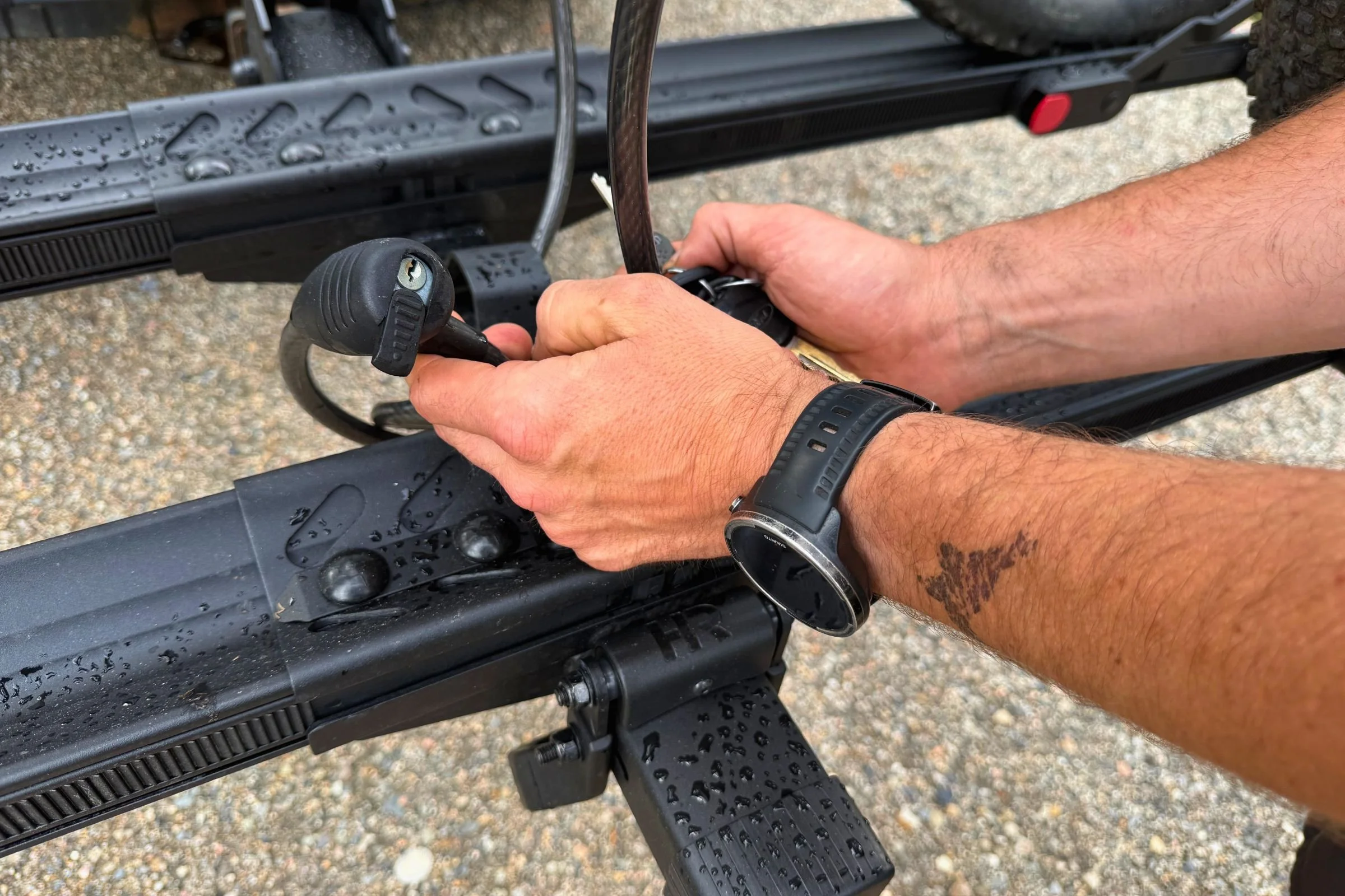 A person using a wrench on the integrated lock components of a Hollywood Racks CrossTrack Hitch Bike Rack.