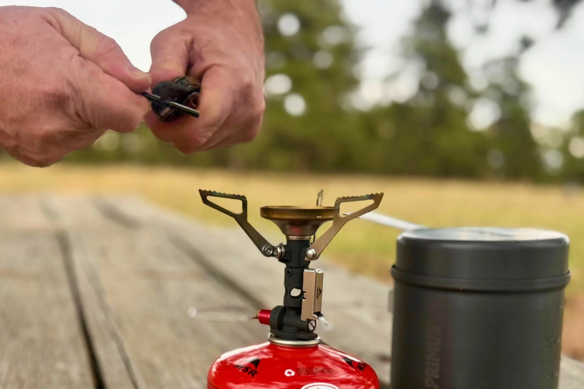 A tester strikes the Gerber Stakeout Spark’s ferro rod above a backpacking stove.