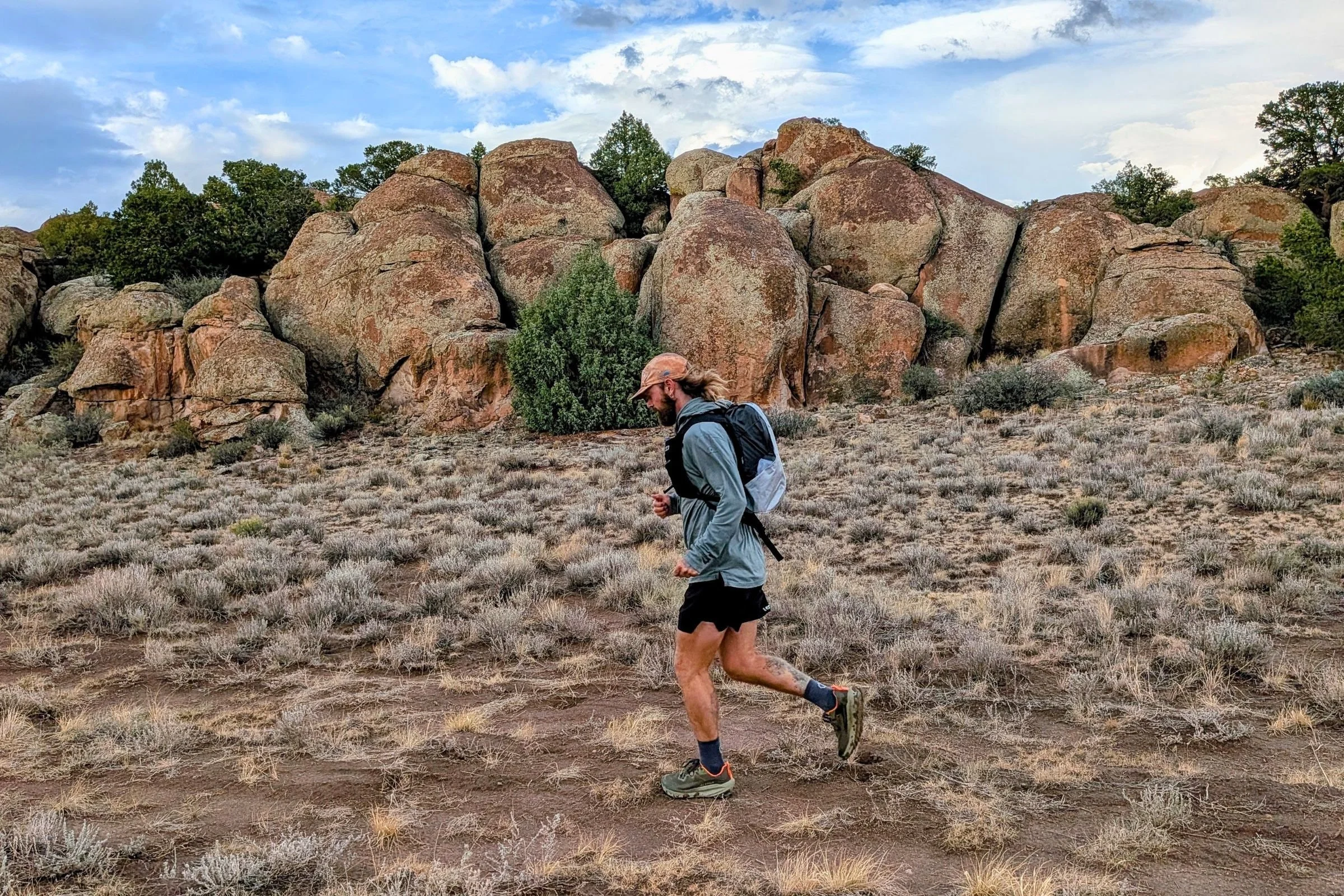 Man running in Altra Olympus 7 shoes on soil and grass.