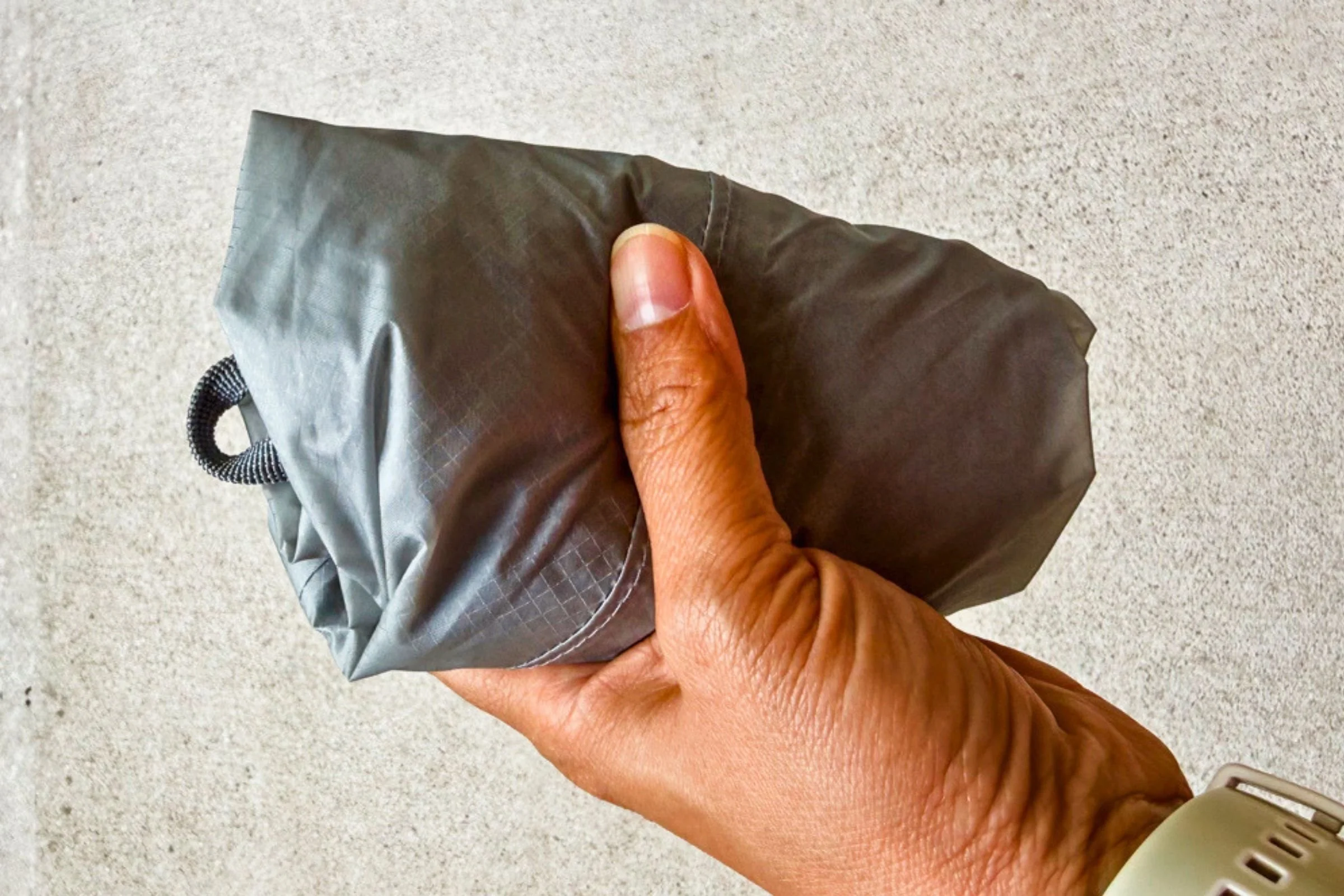 A hand holds the Sea to Summit Ultra-Sil Dry Daypack rolled into a compact bundle