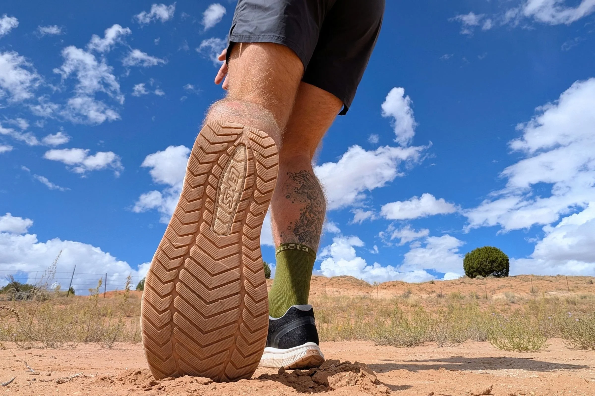 Man wearing Lems ZENSPEED+ shoes while walking on a dirt road.