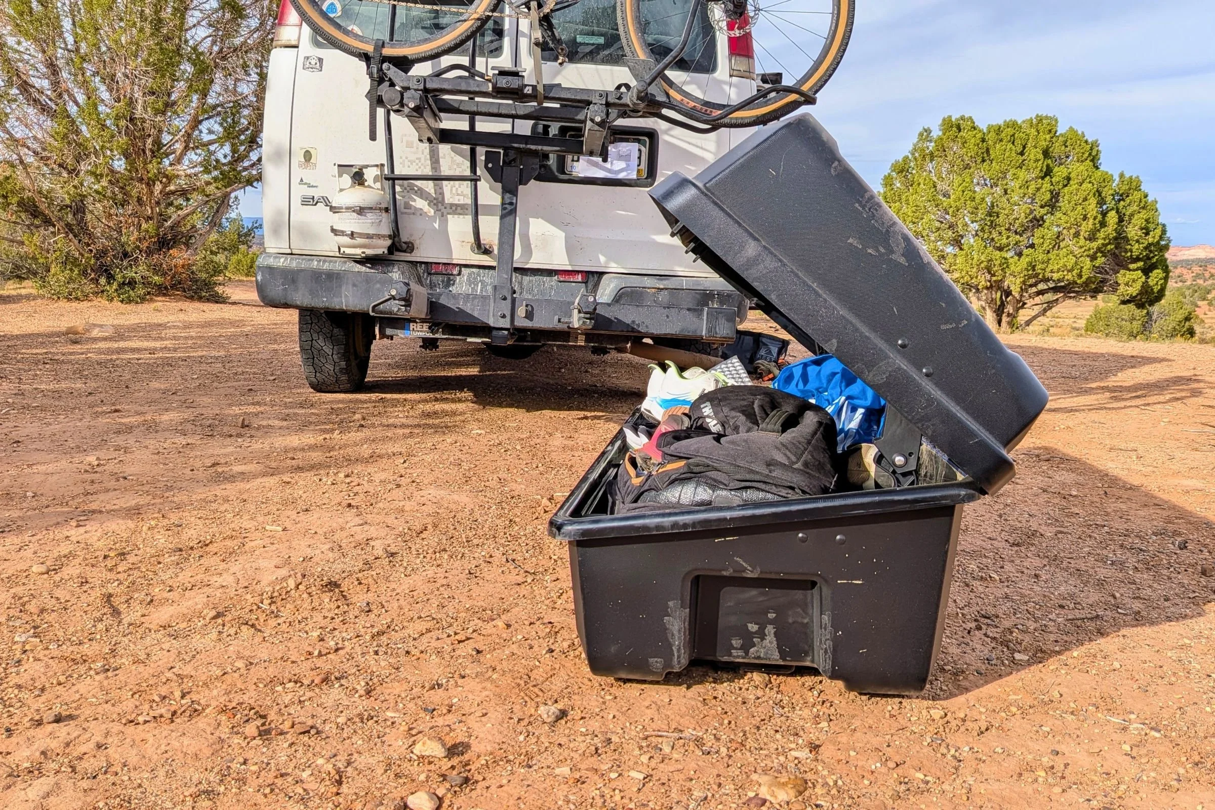 Yakima EXO GearLocker removed from the SwingBase and open on the desert floor behind a van.