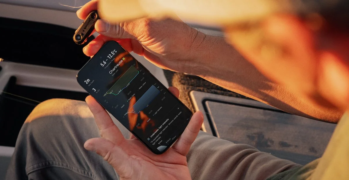 A person holding a smartphone with the COROS app and the COROS HYDROP