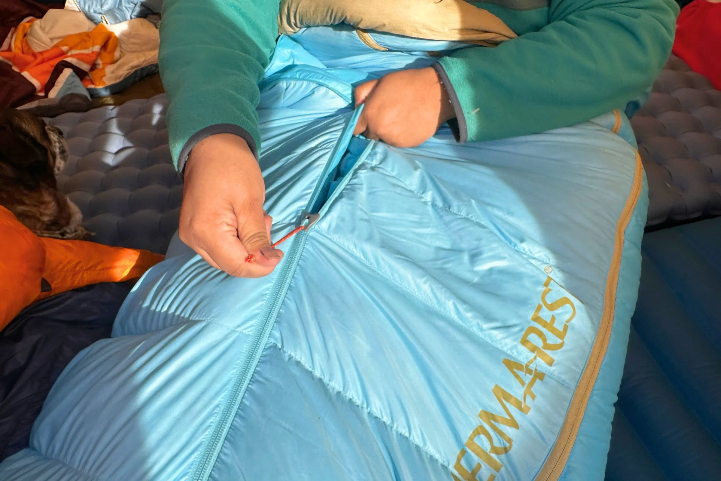 Unzipping the WarmZip, a zipper at the center of the sleeping bag that runs vertically down to the footbox.
