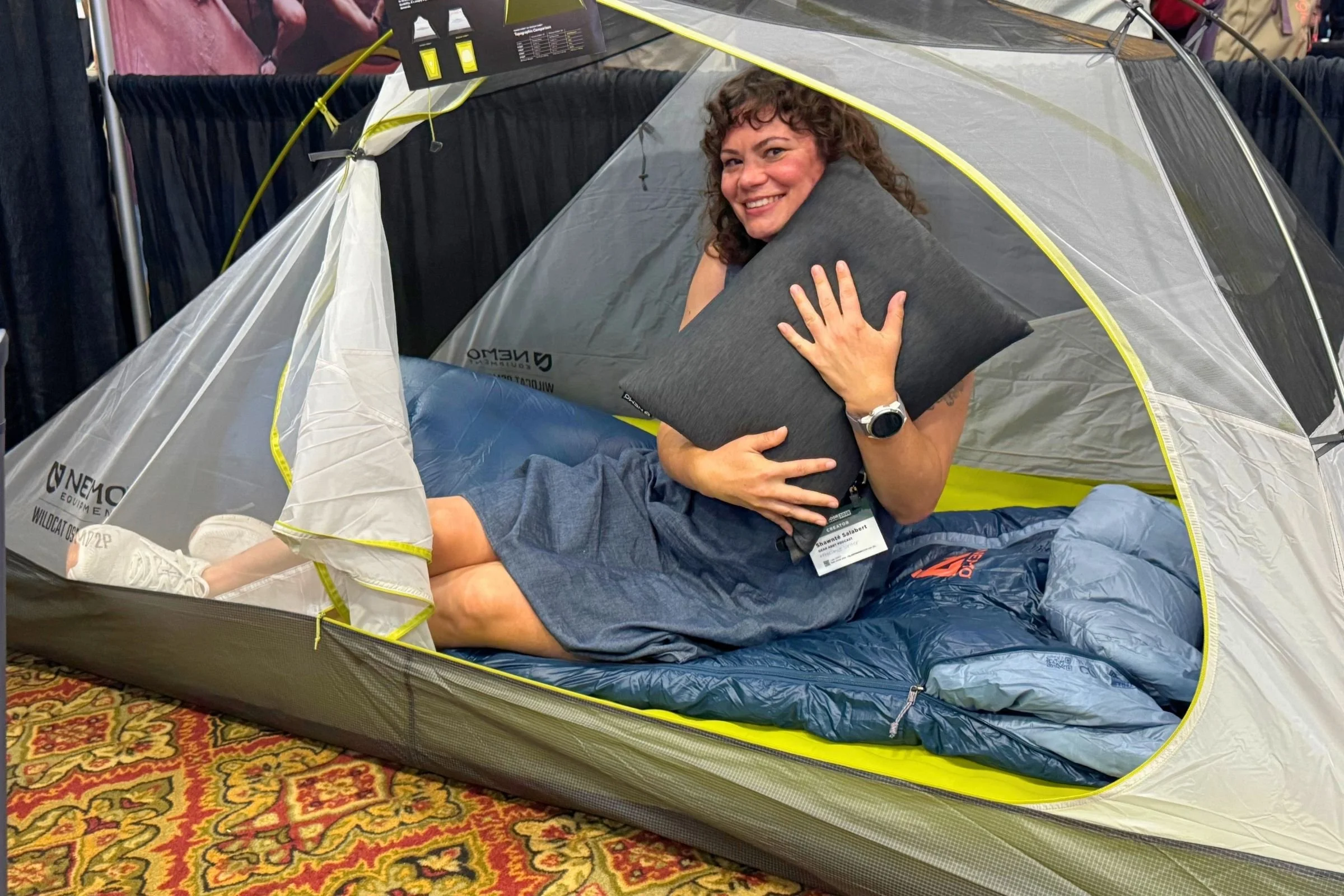 A woman sits inside a tent beside a pillow at the 2026 Outdoor Media Summit.
