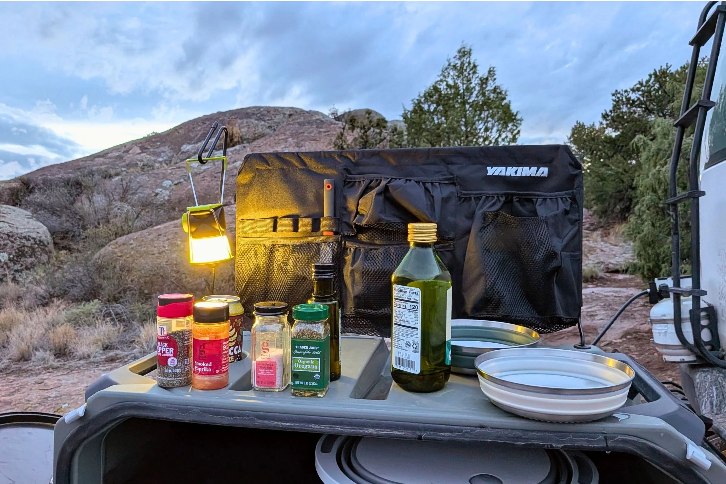 Yakima EXO OpenRange with a storage caddy and lantern hanger, displaying a camping stove and food.