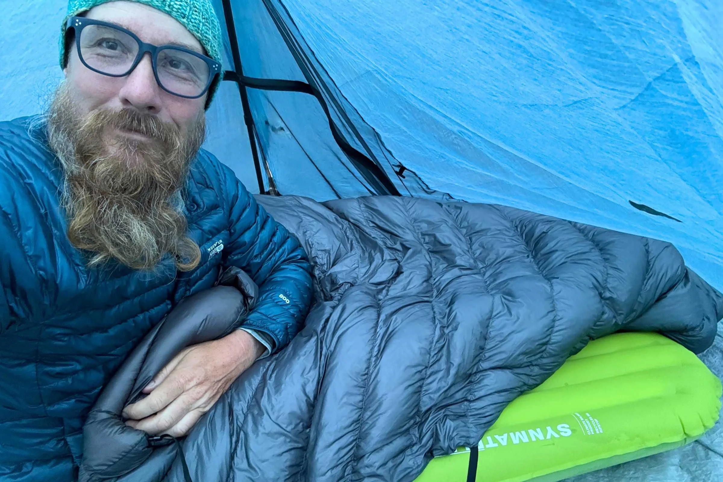 Backpacker inside tent using EXPED Ultra 6.5R Mummy sleeping pad with down quilt during overnight camping test