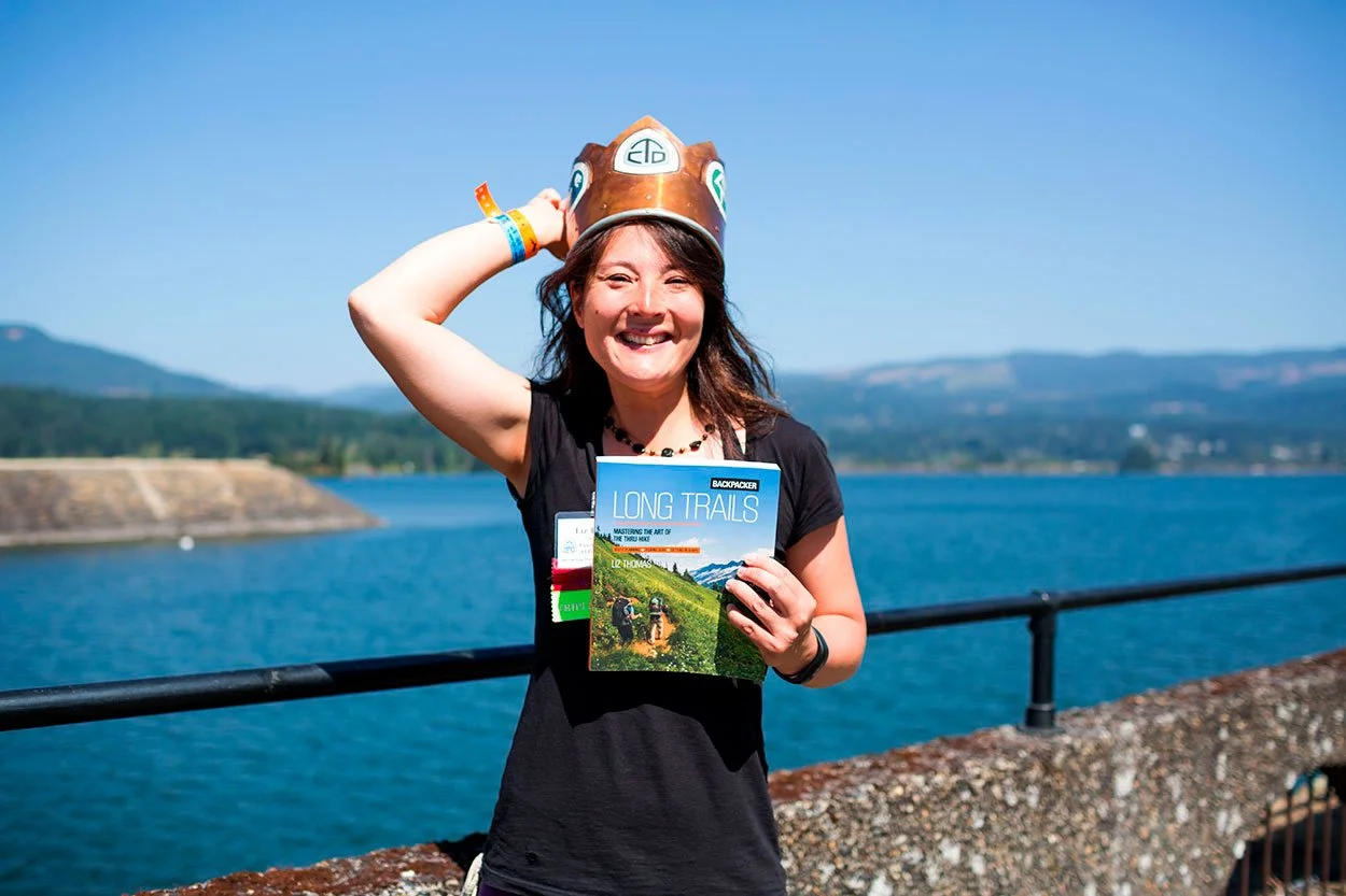 woman wearing a crown and holding a long trails book at the columbia river