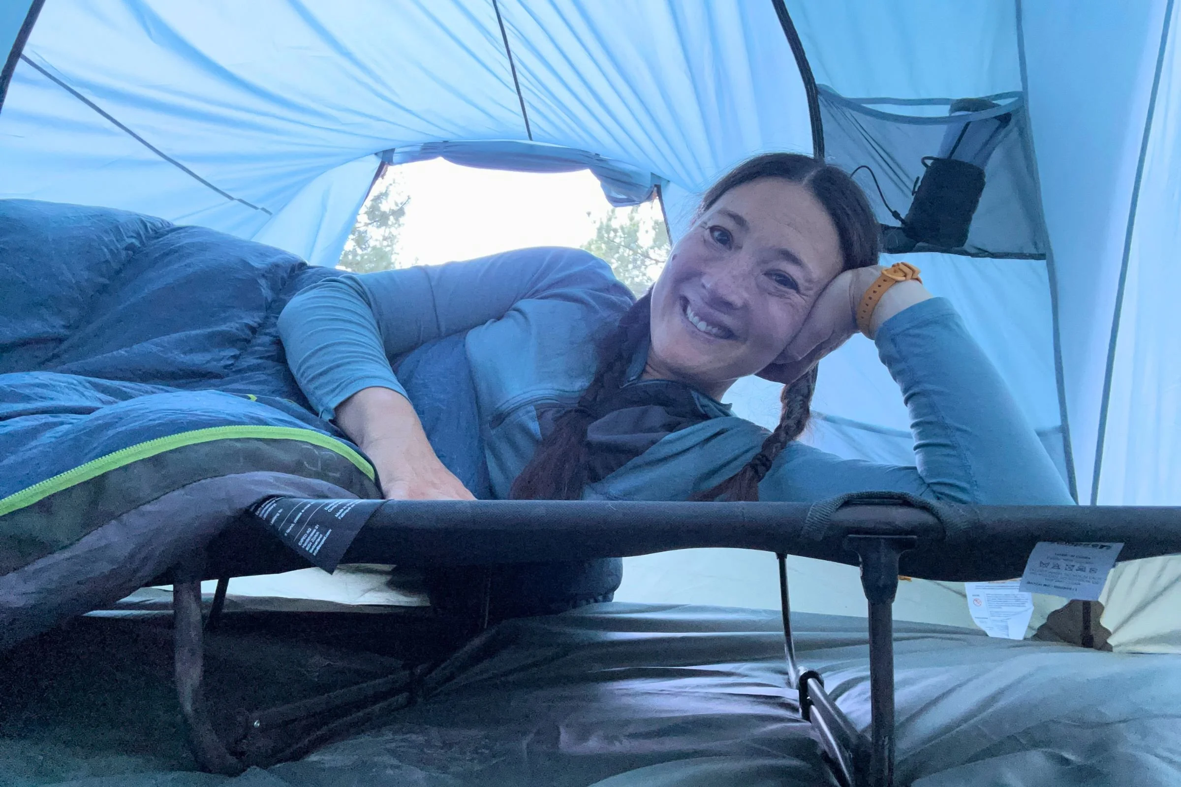 Liz Thomas reclining on a camping cot inside a tent.