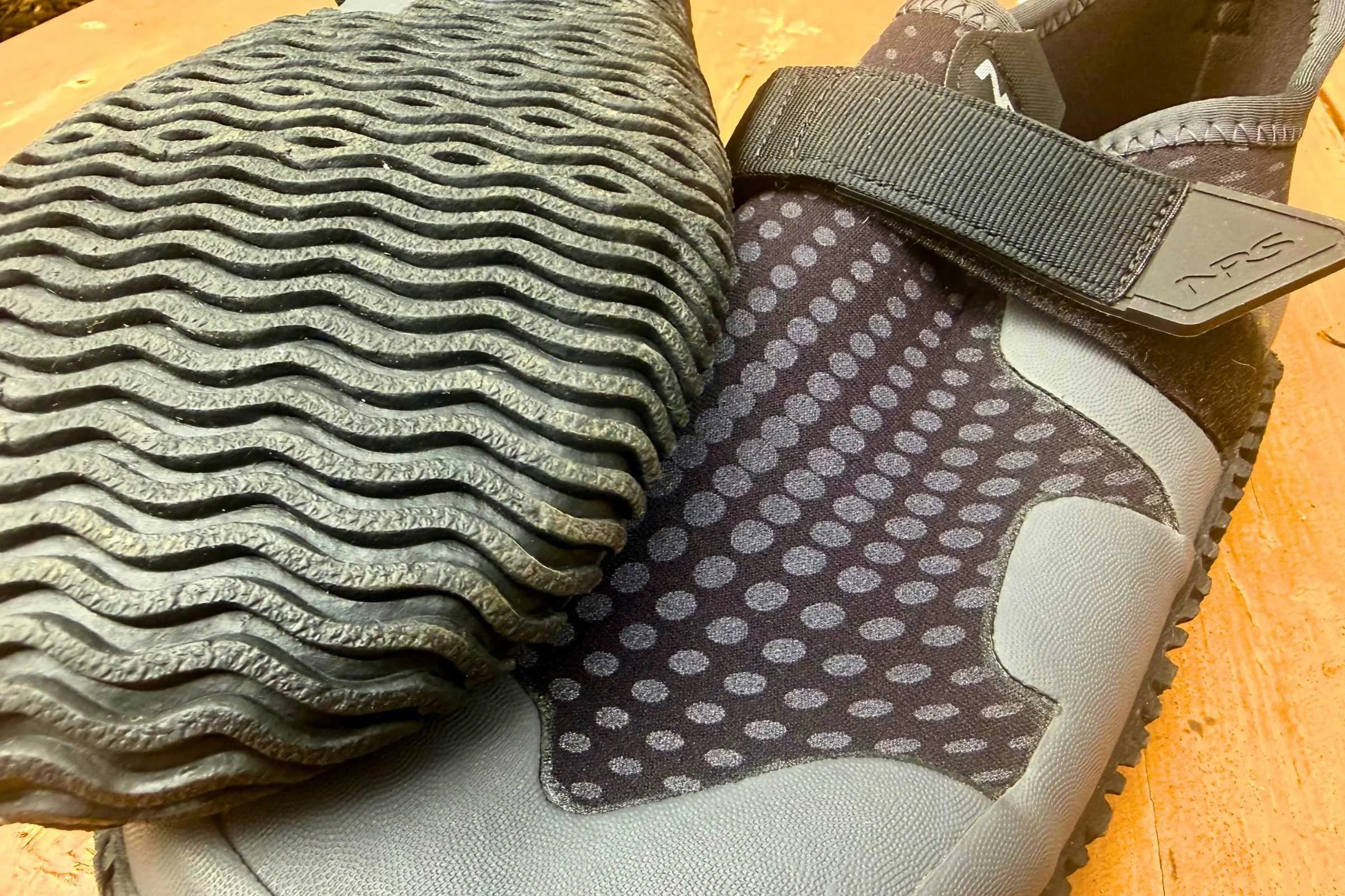 a close-up of the upper and outsole of a pair of black nrs kicker wetshoes