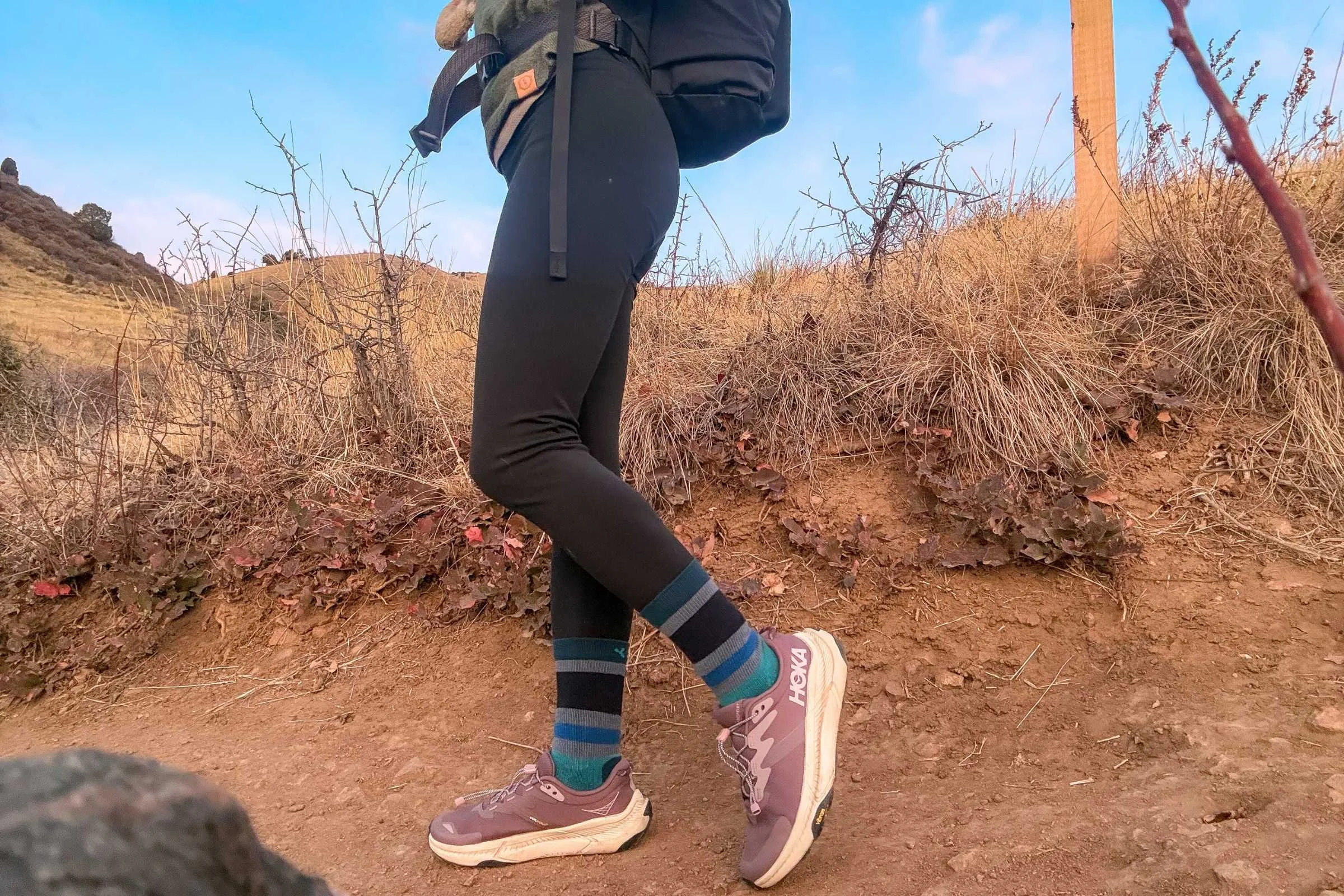 Woman wearing HOKA Transport 2 trail shoes on a dirt hiking trail