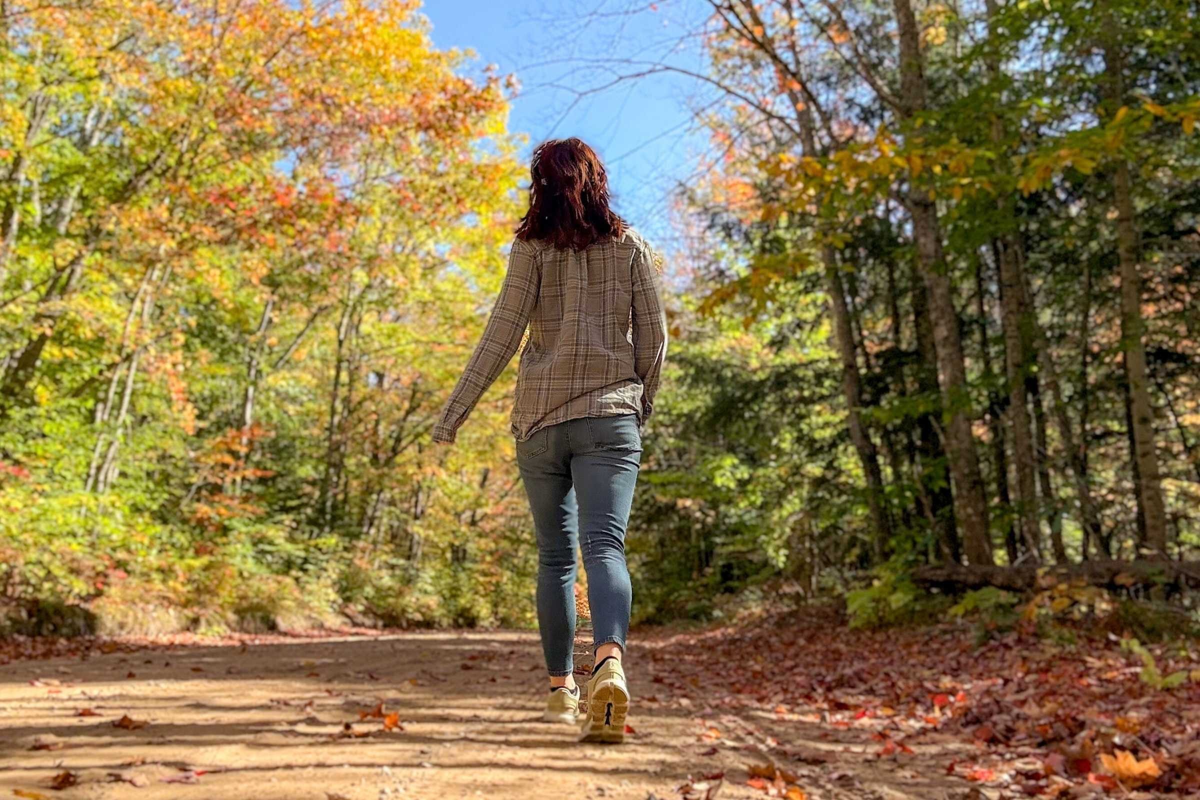 woman walks on dirt road wearing green on cloud 6 shoes