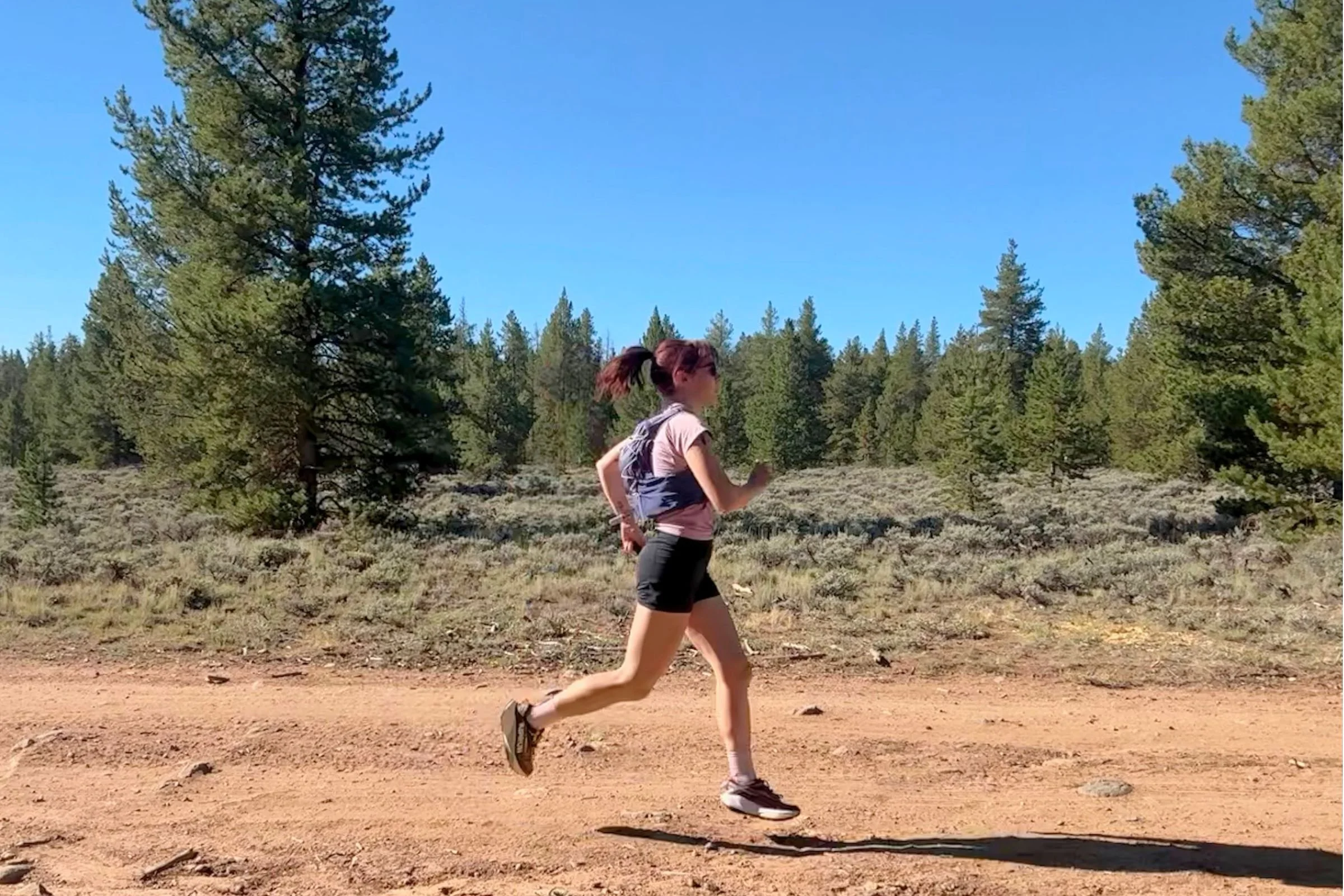 Woman testing a Nathan VaporAir pack while running on a trail.