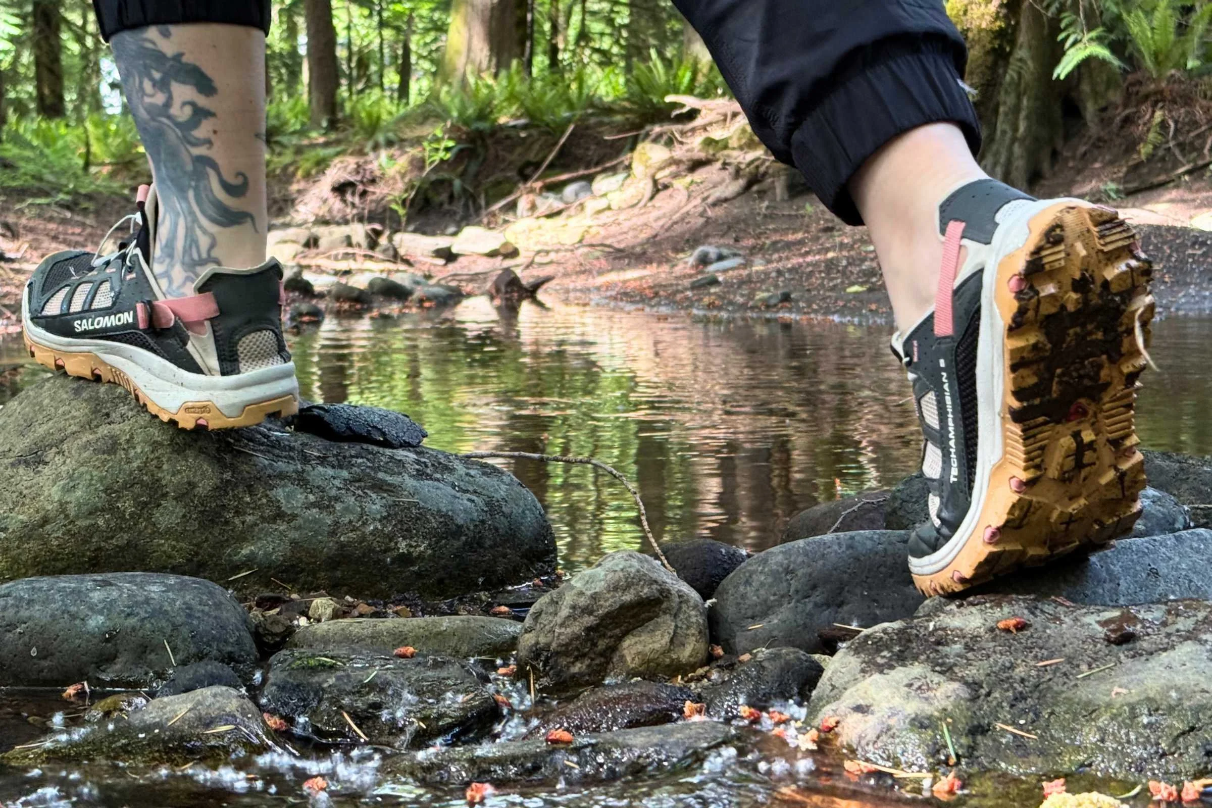 crossing a stream on rocks wearing the Salomon Techamphibian 5 water shoes. You can see the aggressive tread on the shoe.