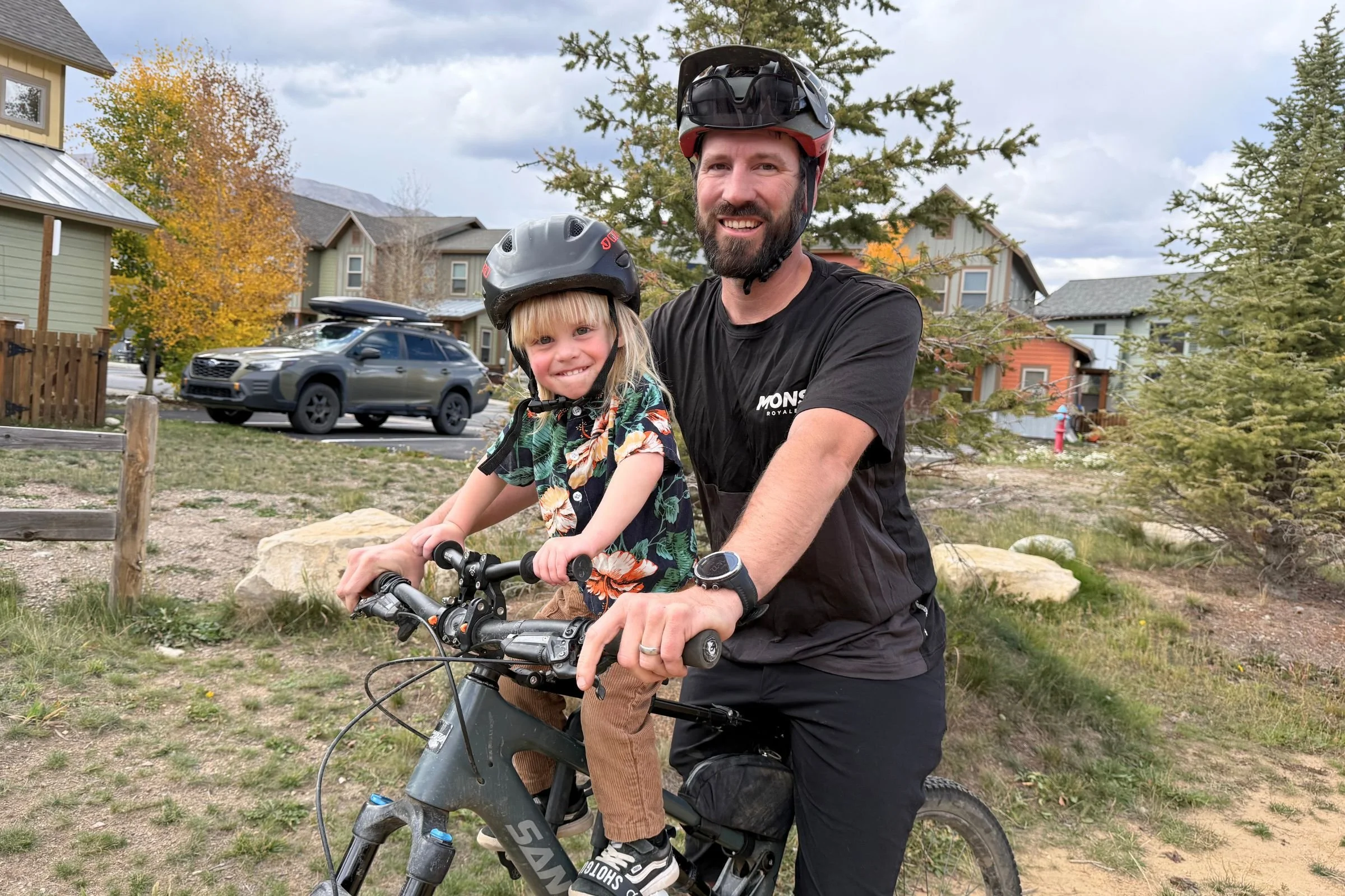 A father and son on a grey Santa Cruz mountain bike, with the child in the Kids Ride Shotgun Shotgun Pro EVO 2-in-1 bike seat.