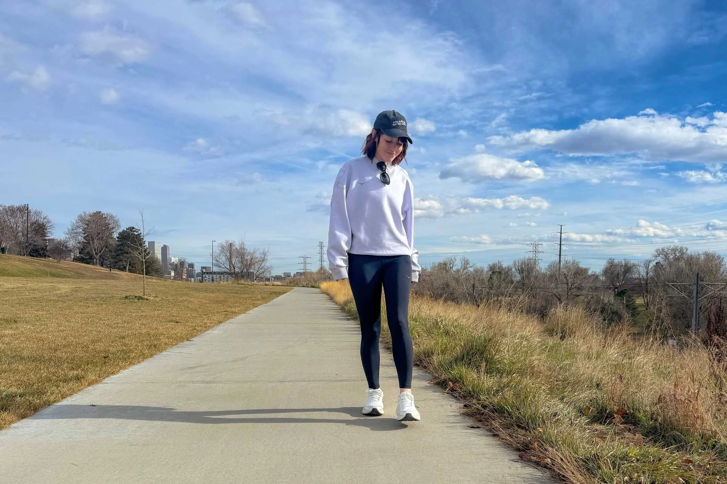 woman walks on bike path in white hoka bondi sr shoes