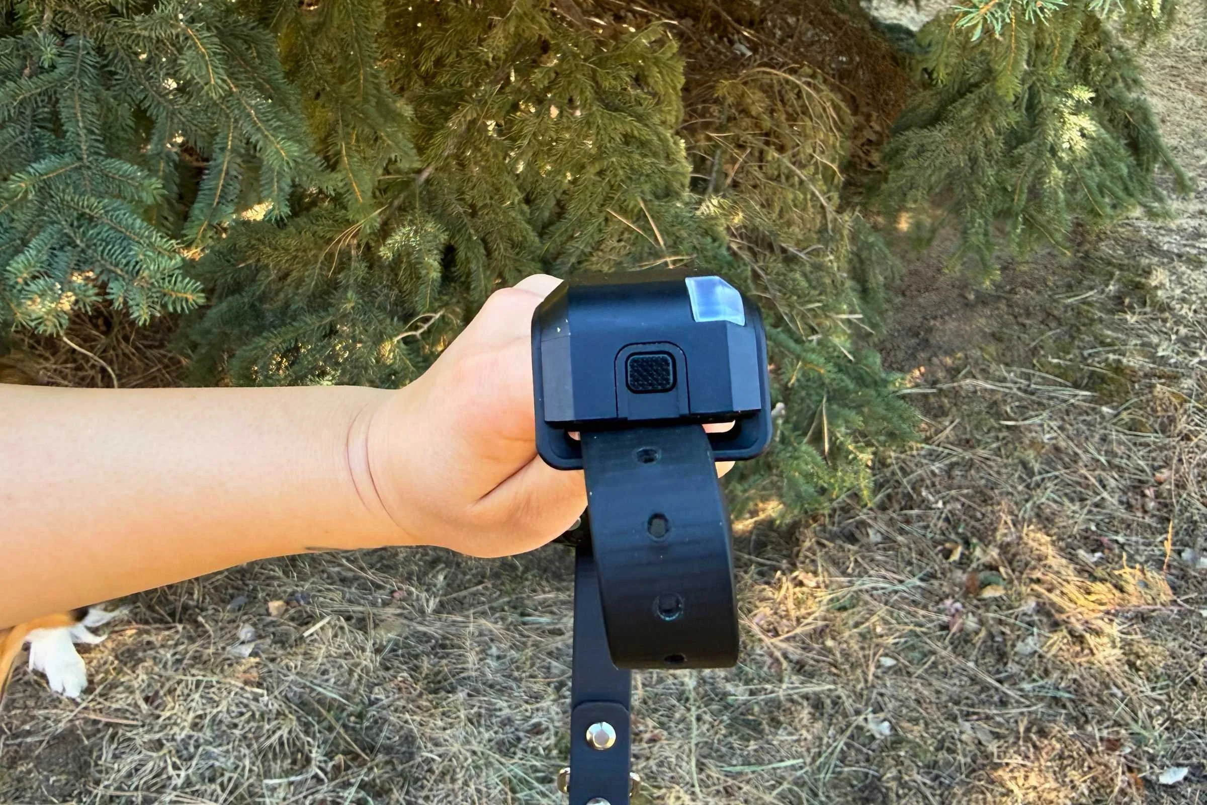 Person holding the Garmin Alpha LTE sideways showing the button