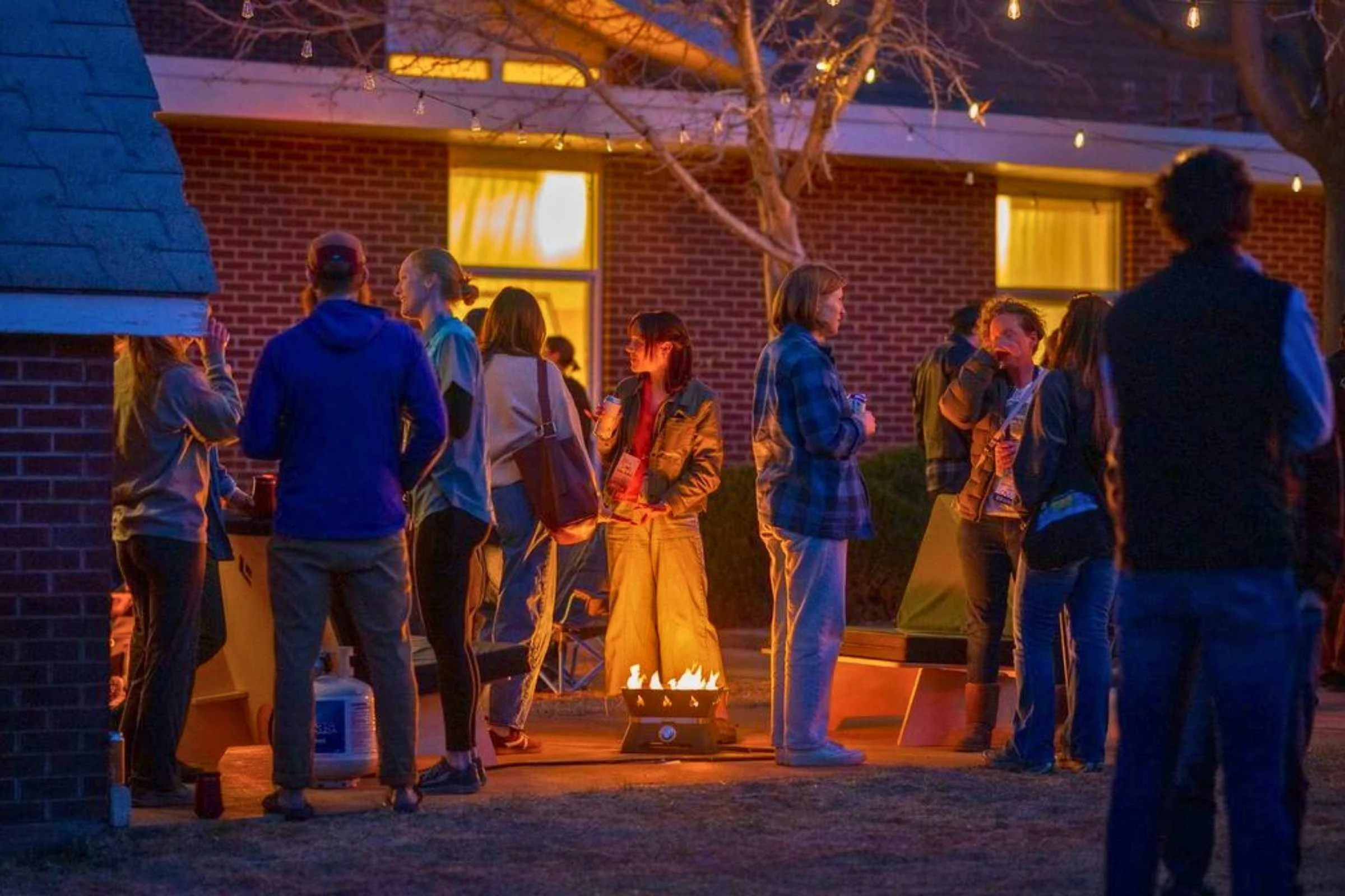 Treeline reviewer Becca chatting with other attendees around the campfire during an evening gathering at the Outdoor Market Alliance show.