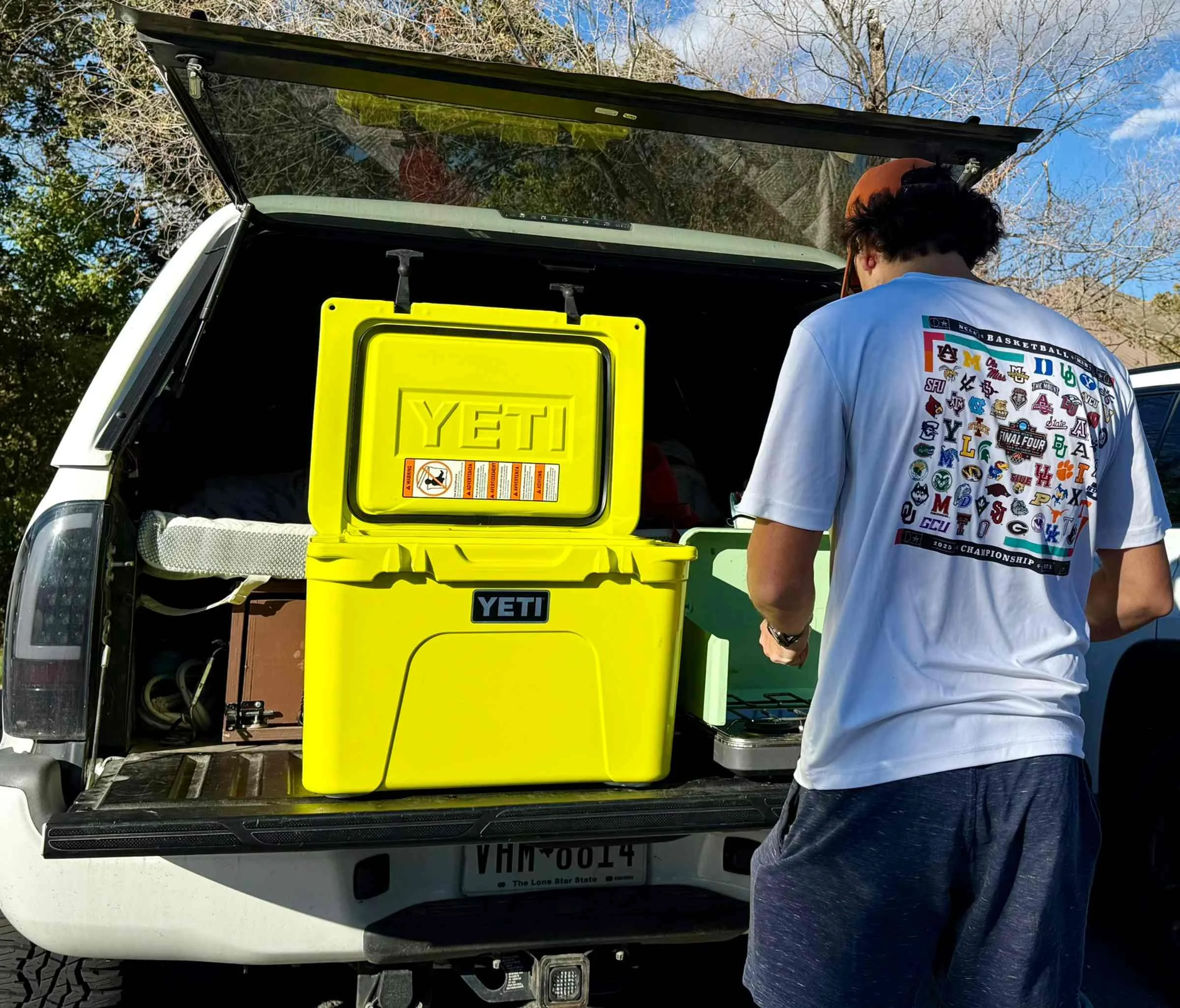 The author cooking on the tailgate of his truck while storing food and cooling it in a bright yellow YETI Tundra.