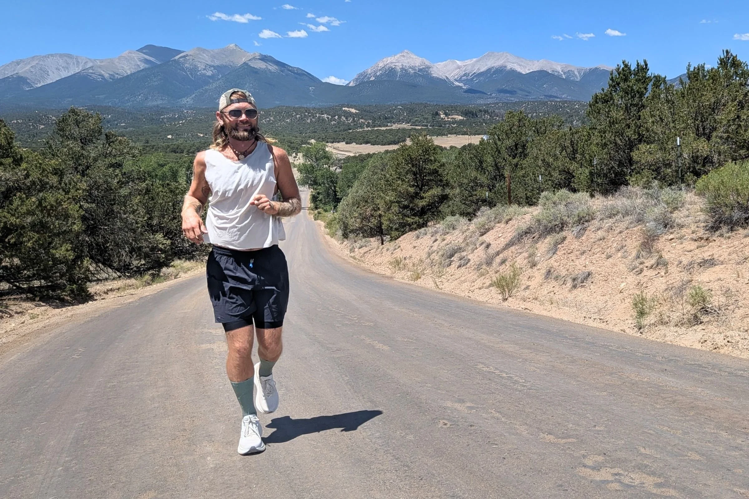 A man running on a road with mountains in the background, wearing the Saucony Triumph 24 Road Running Shoe.
