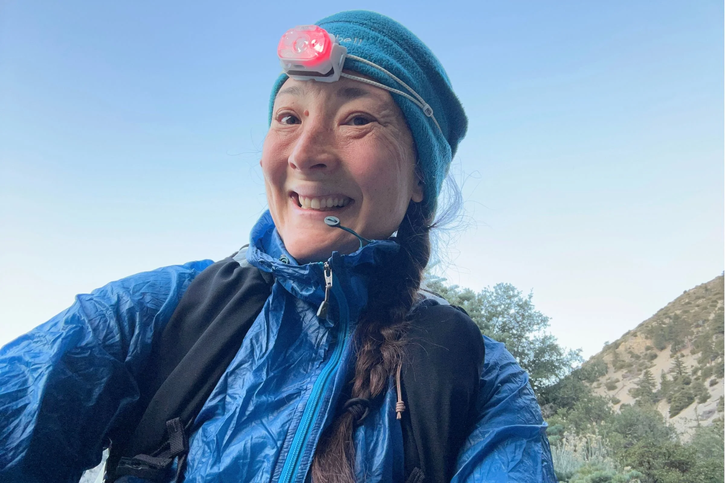 The Petzl Swift LT headlamp on a backpacker at dawn in red light mode