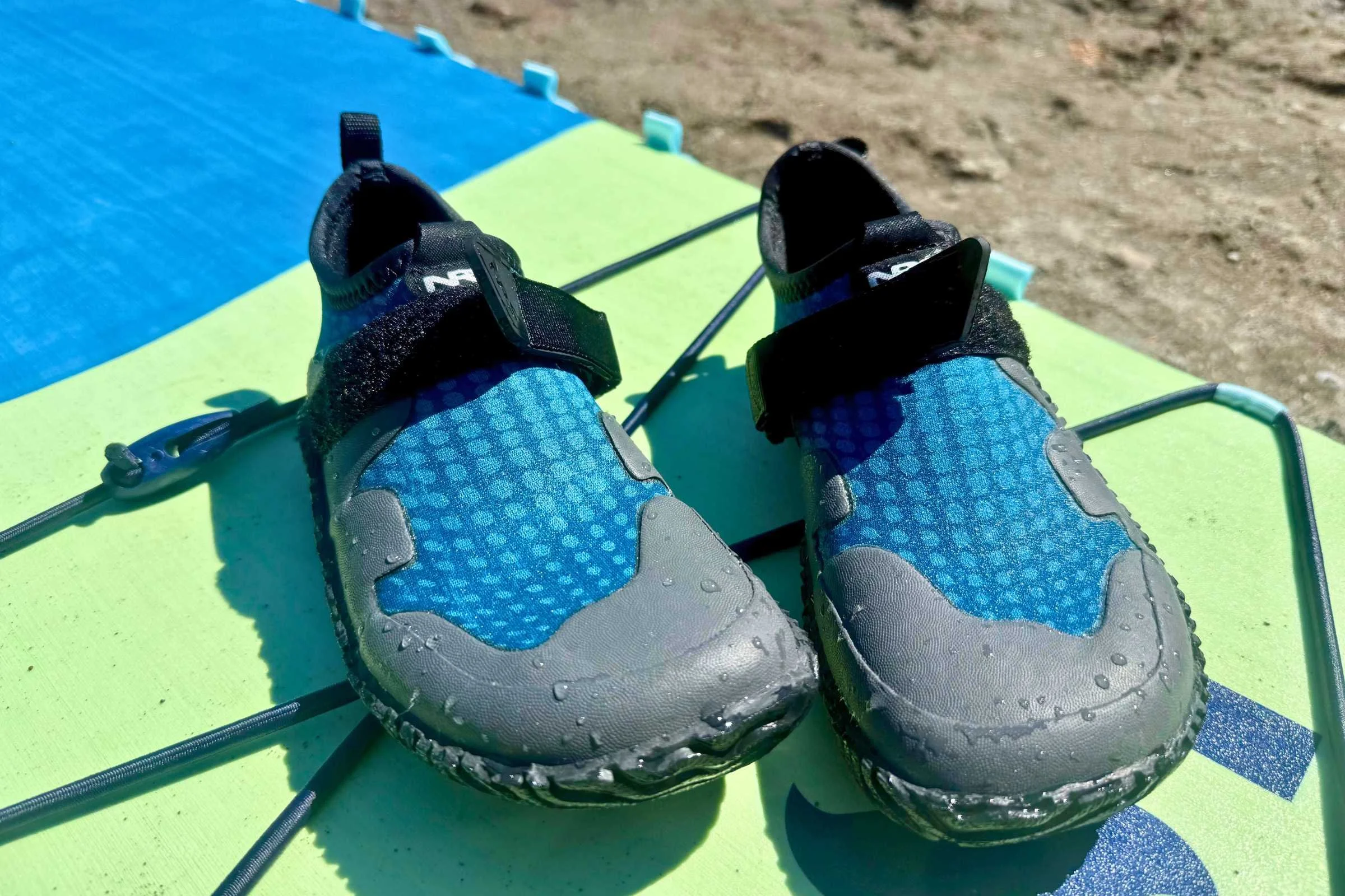 a pair of blue nrs kicker wetshoes on a paddleboard