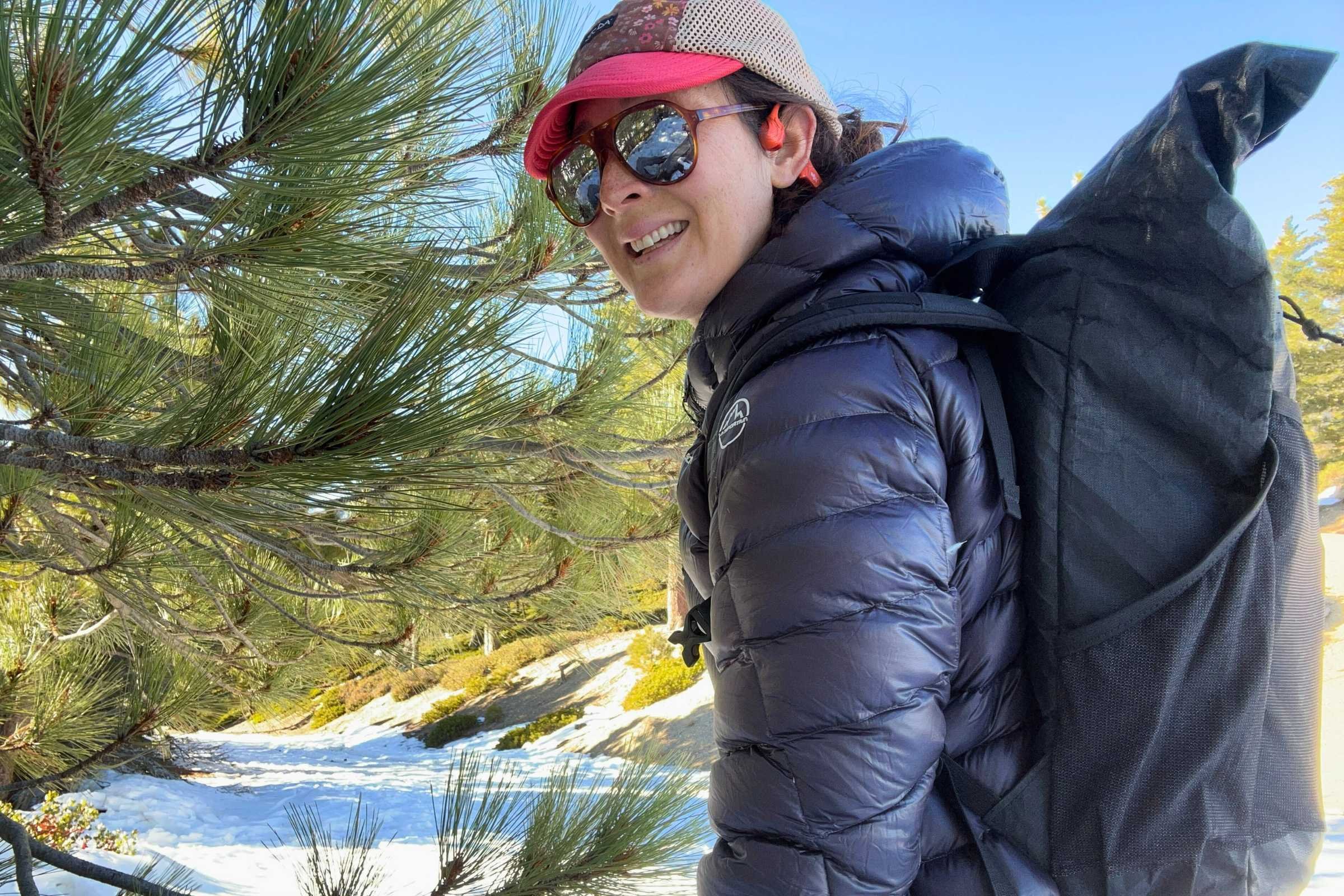 Backpacker wearing La Sportiva Lumina down jacket on snowy forest trail