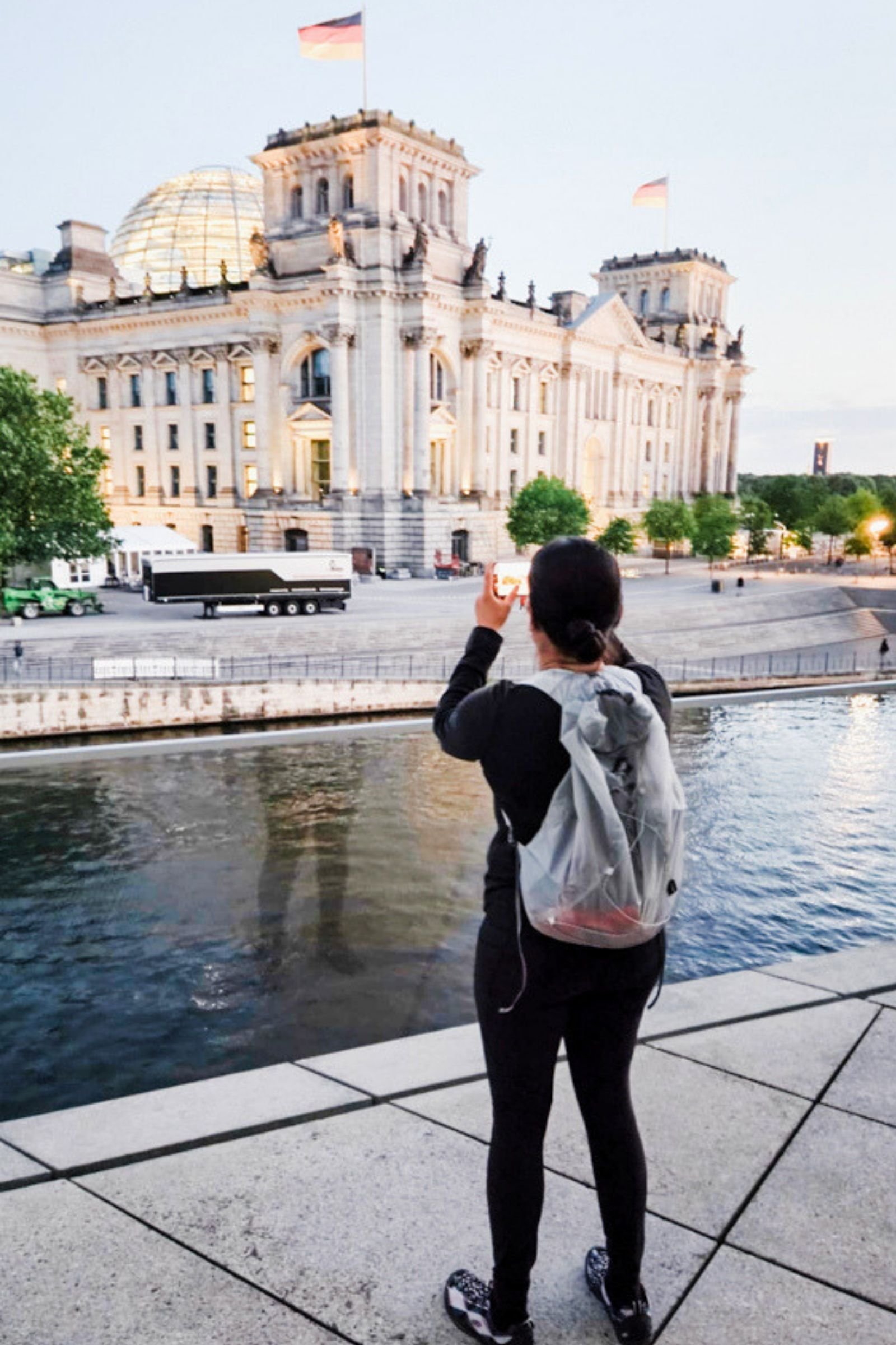 A person wearing the Sea to Summit Ultra-Sil Dry Daypack stands beside a river in a city