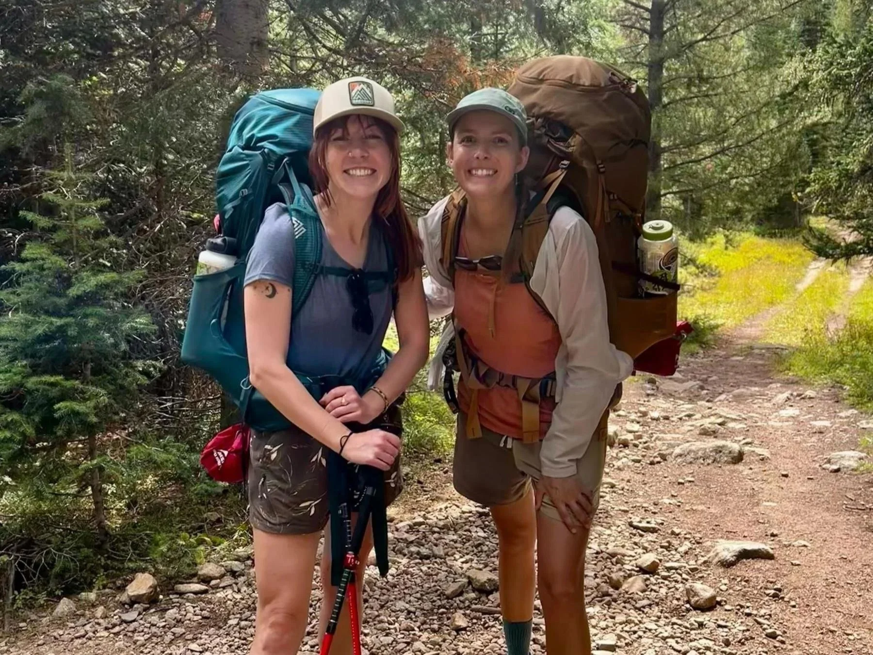 Two women wearing backpacking backpacks in a forest