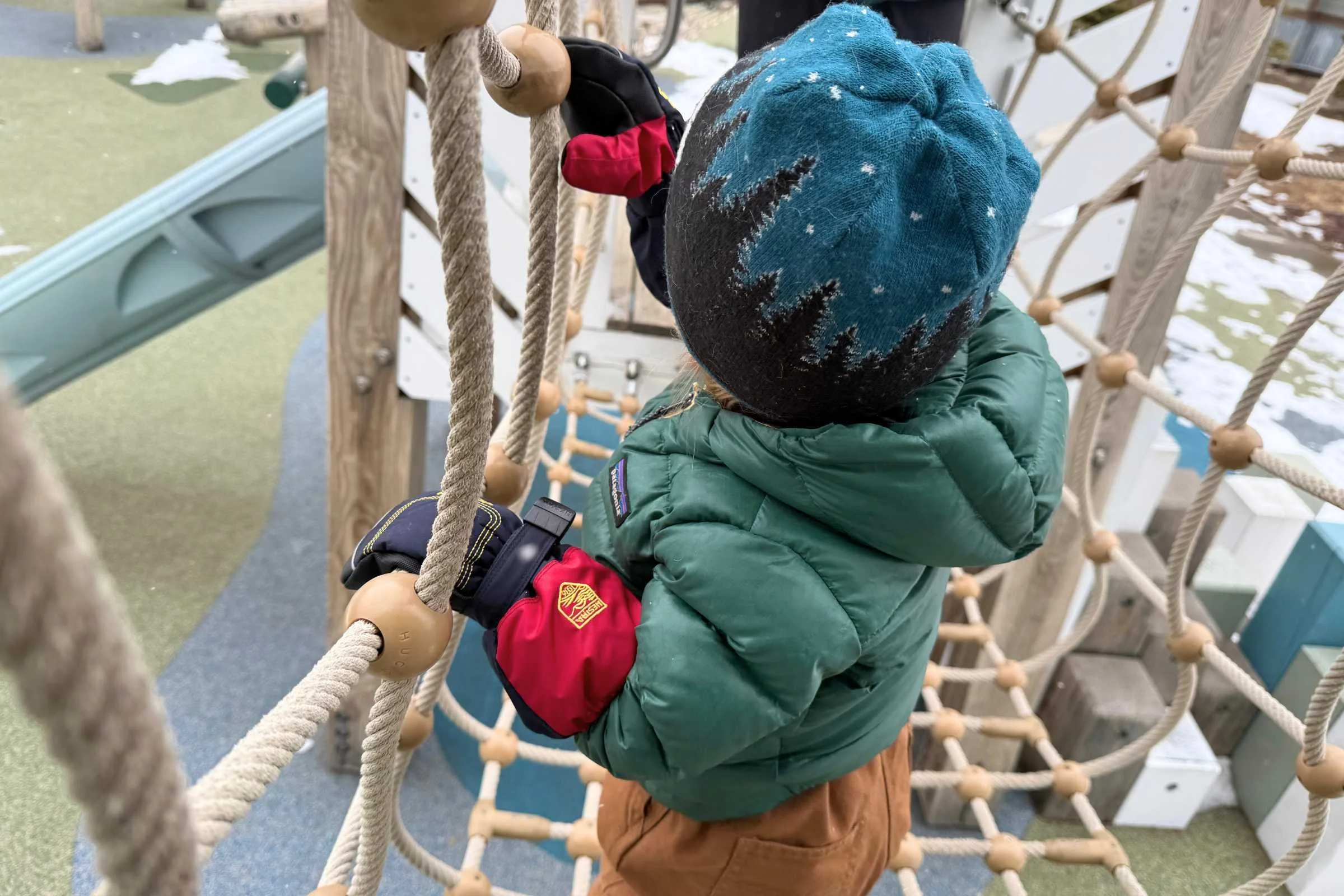 Child wearing Hestra Baby Zip Long Mitts while playing on playground