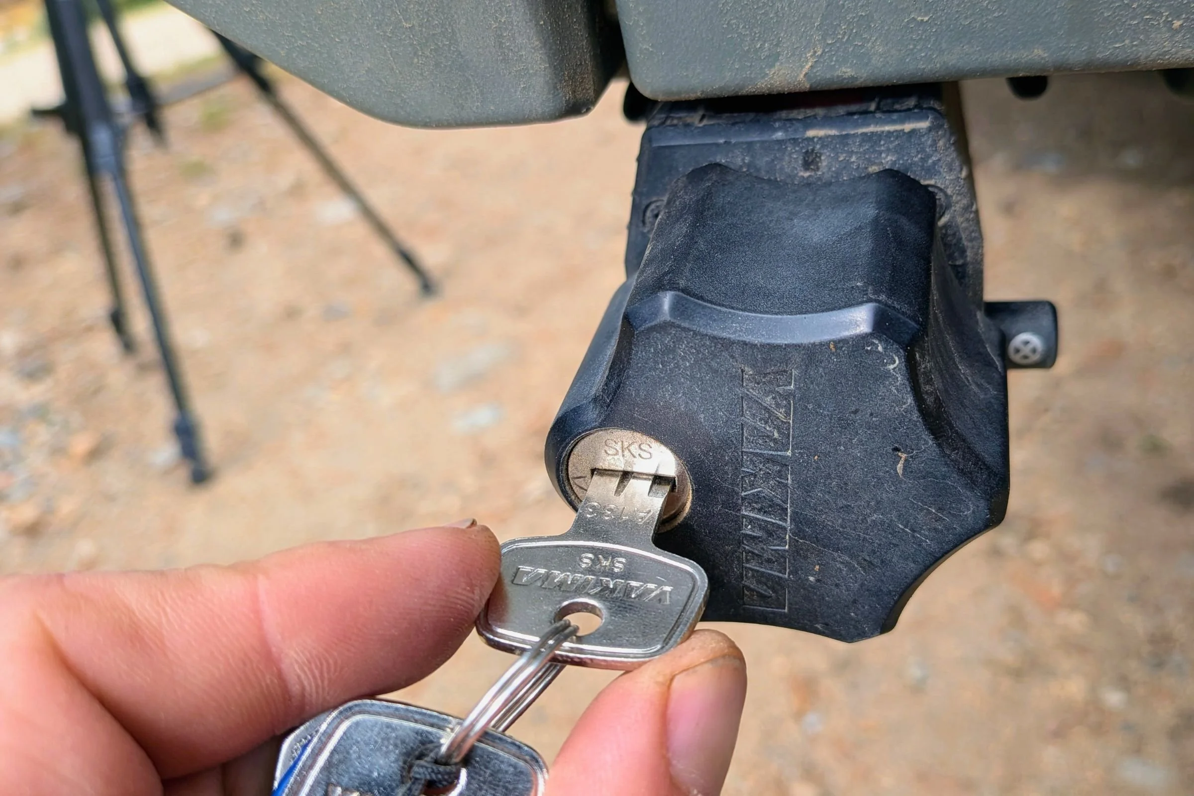 A person’s hand holds a key near a vehicle with a Yakima EXO Swing.