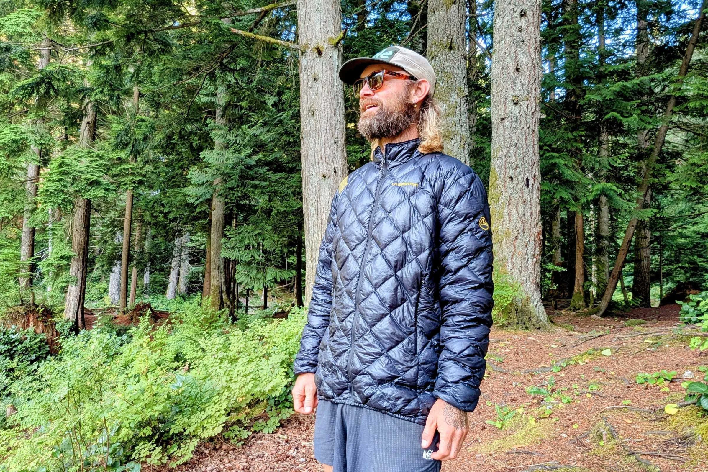 a man wearing the la sportiva lumina 100 down jacket in the woods