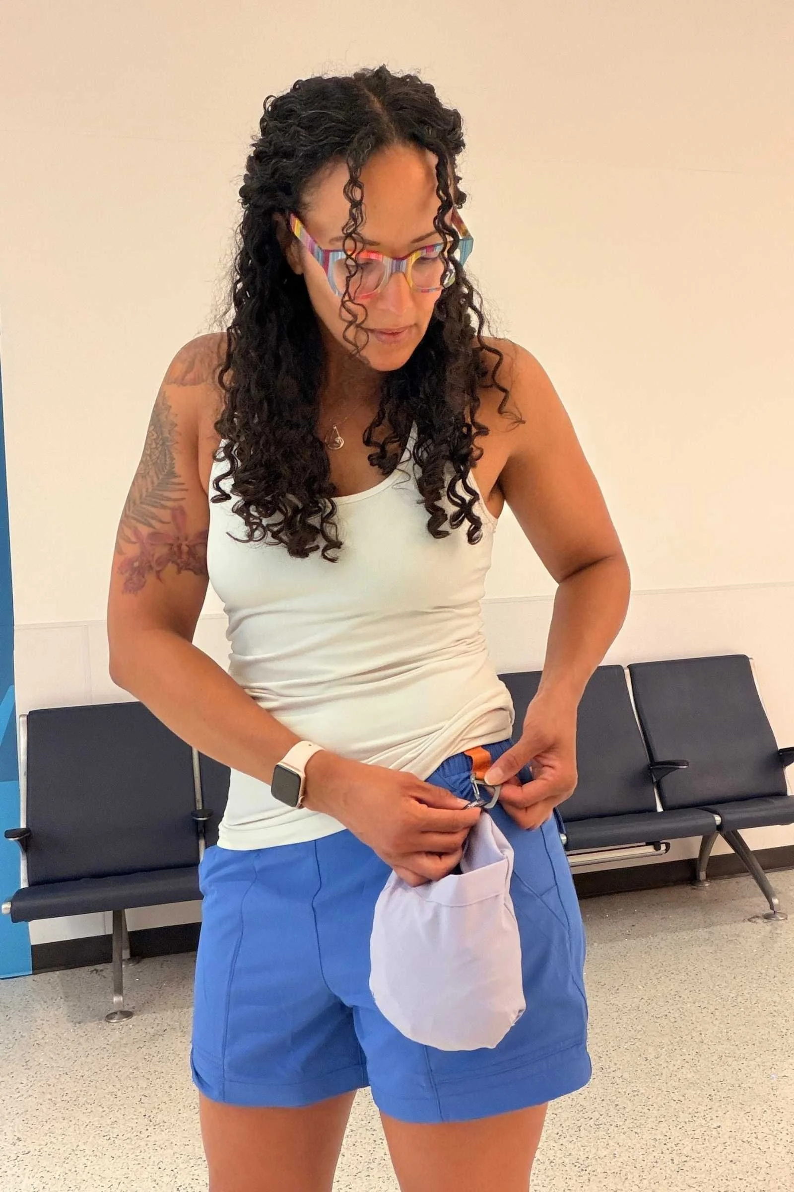 Woman wearing Cotopaxi Losdos Zip Off travel pants with legs zipped off and in their stuff pouch in an airport